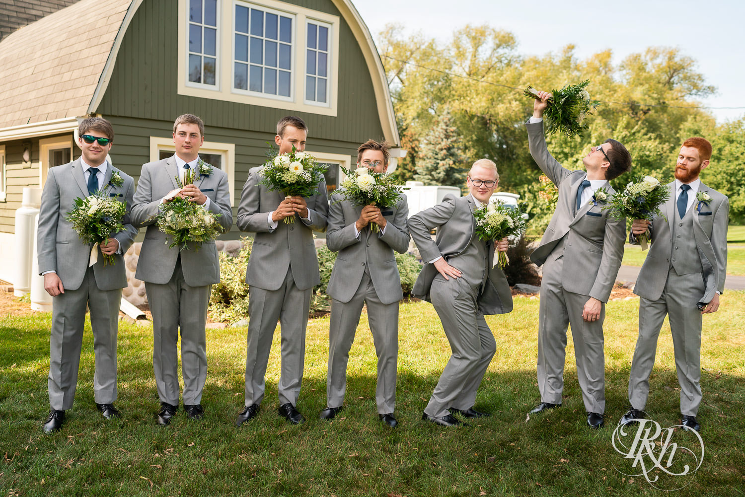 Groomsmen posing with flowers in gray suits.