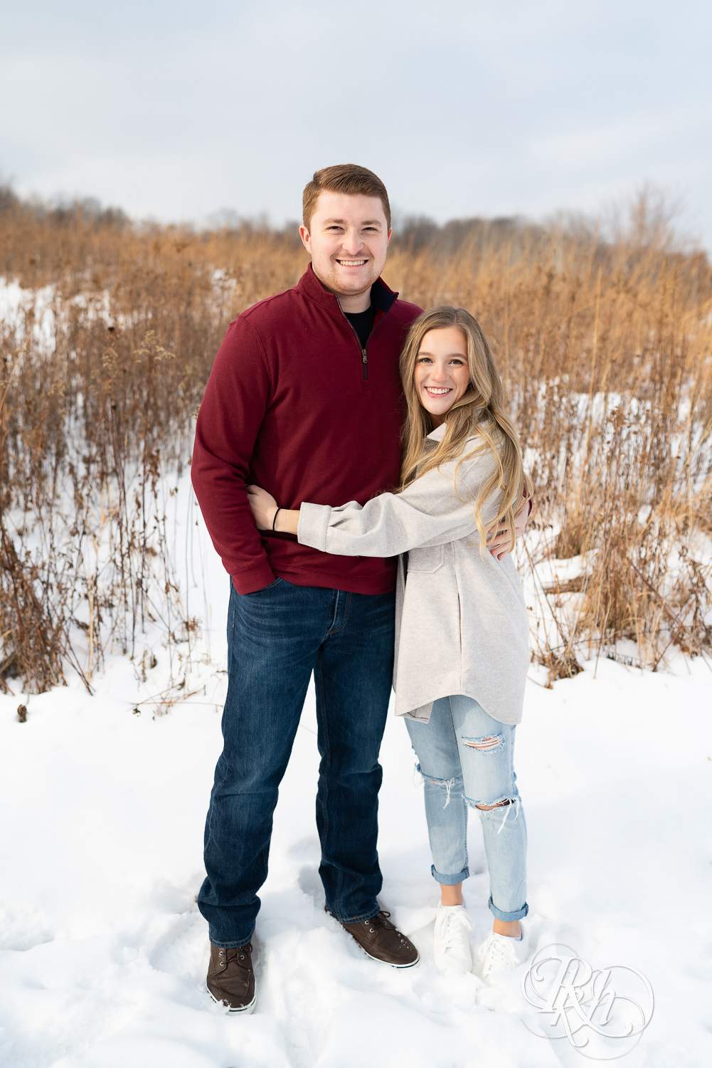 Couple hugging looking at camera in the snow.
