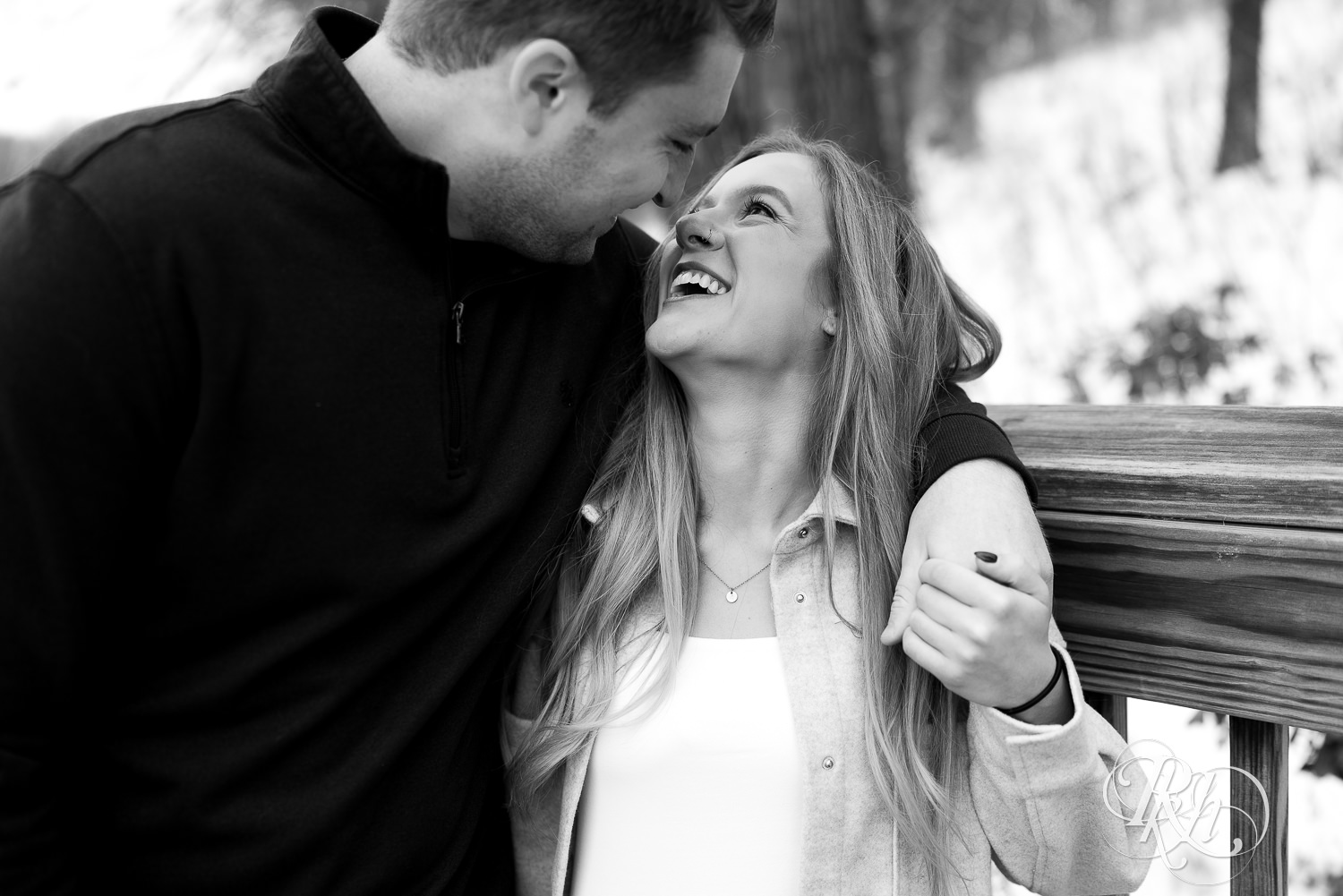 Candid winter engagement photography of couple looking at each other laughing.