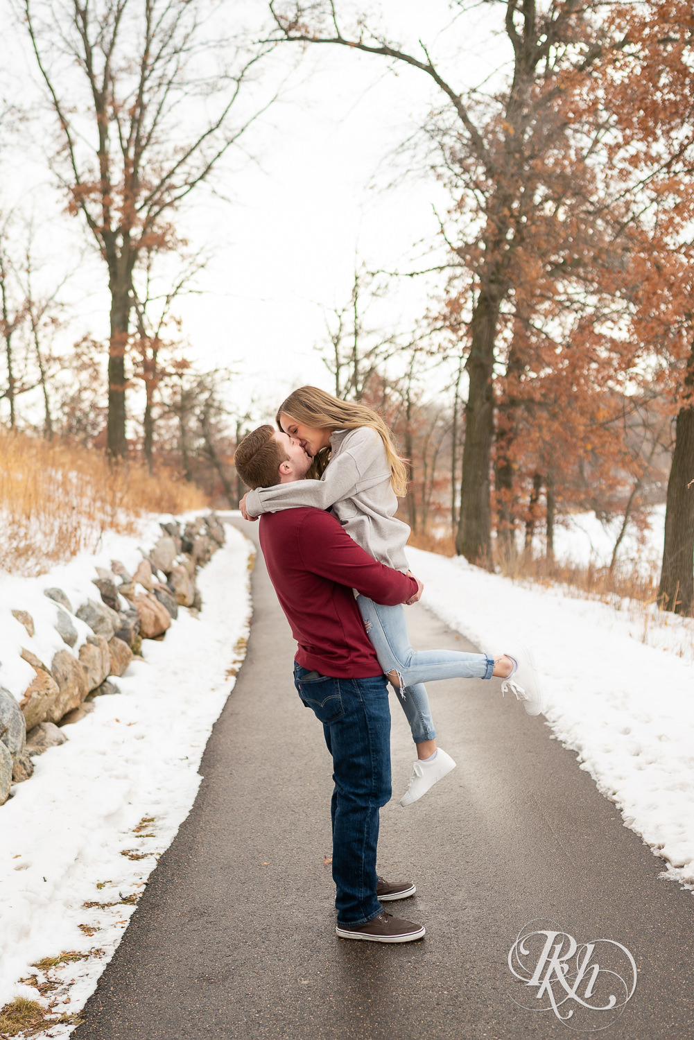 Man lifts and kisses woman in winter engagement photo at Lebanon Hills Regional Park in Eagan, Minnesota