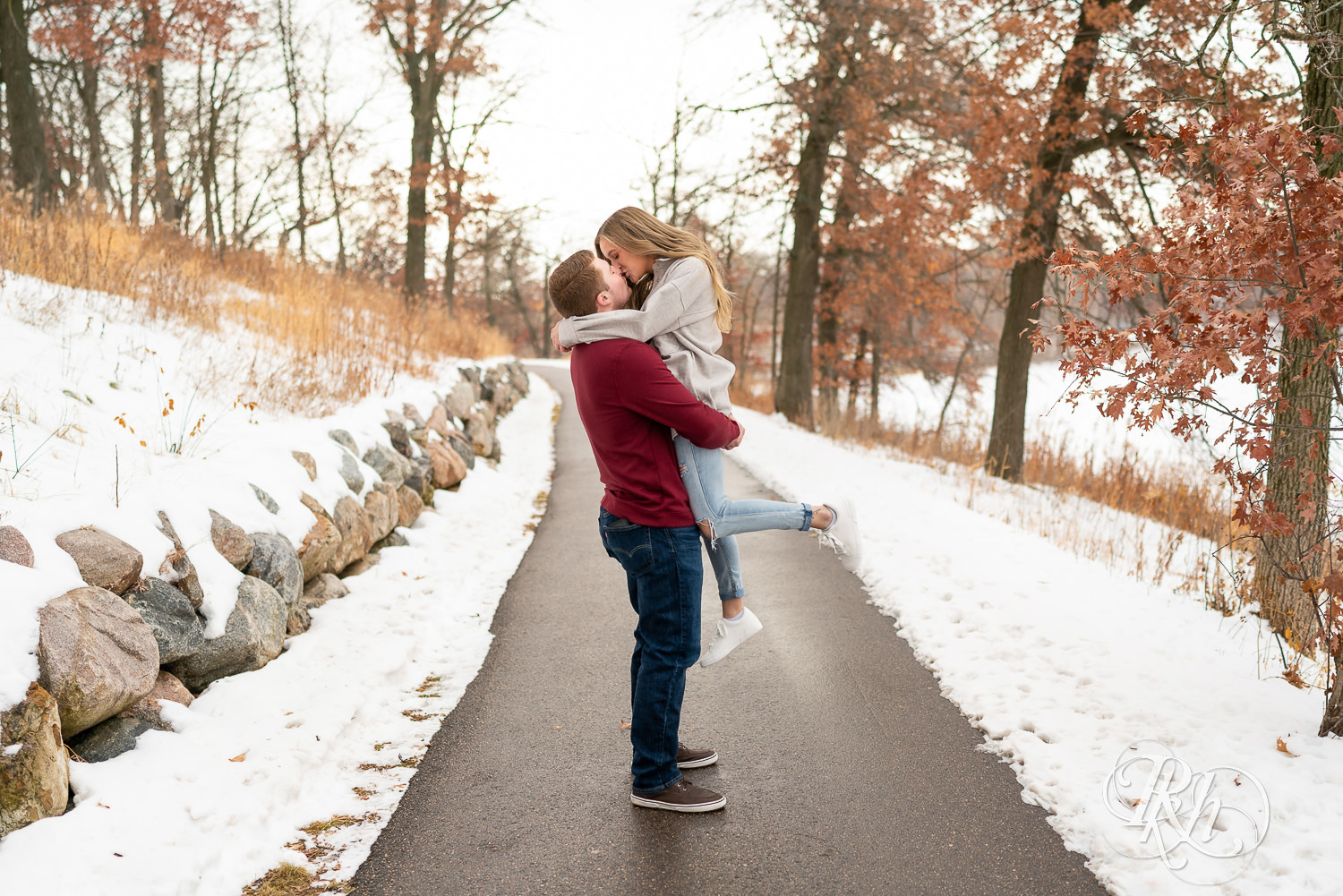 Man lifts and kisses woman in winter engagement photo