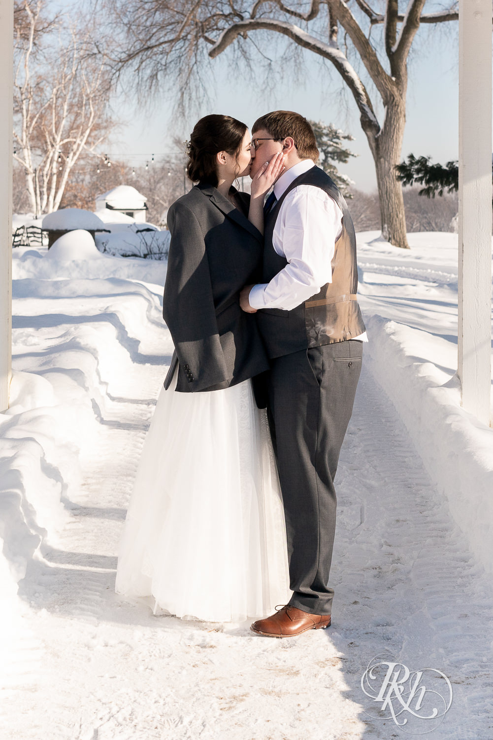 Bride and groom kissing in snow outside at Minneapolis Golf Club in Saint Louis Park, Minnesota.