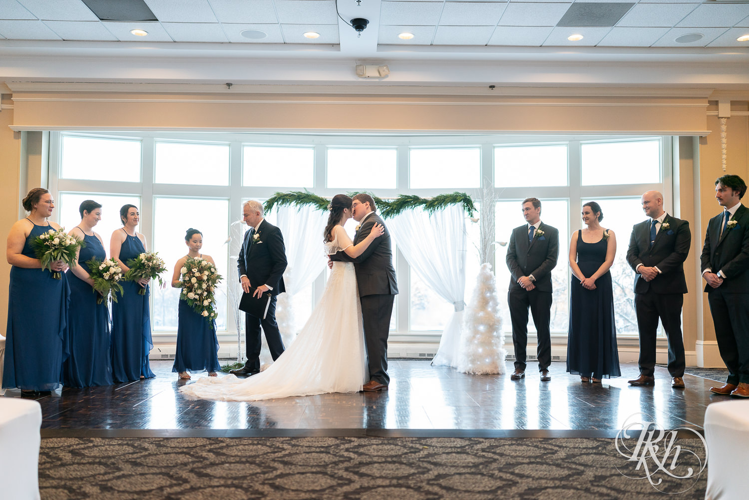 Bride and groom share first kiss at wedding ceremony at Minneapolis Golf Club in Saint Louis Park, Minnesota.