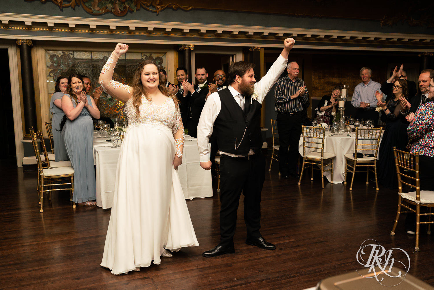 Bride and groom pump fists at grand entrance at Semple Mansion in Minneapolis, Minnesota.