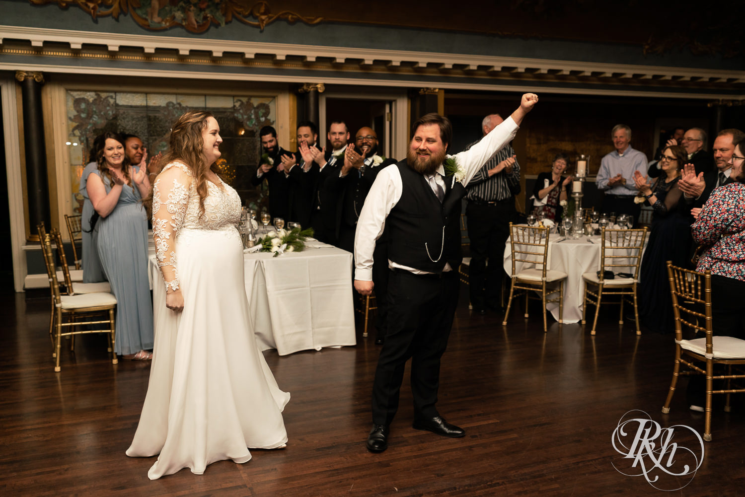 Bride and groom pump fists at grand entrance at Semple Mansion in Minneapolis, Minnesota.