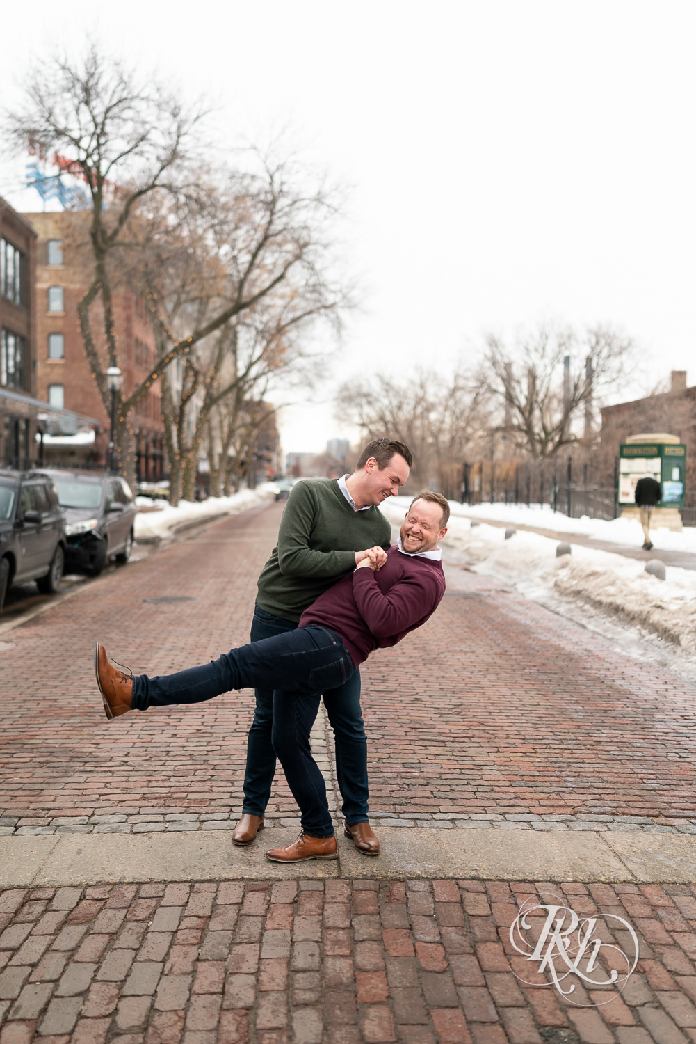 Gay men smile on cobblestone street during the winter in Minneapolis, Minnesota.