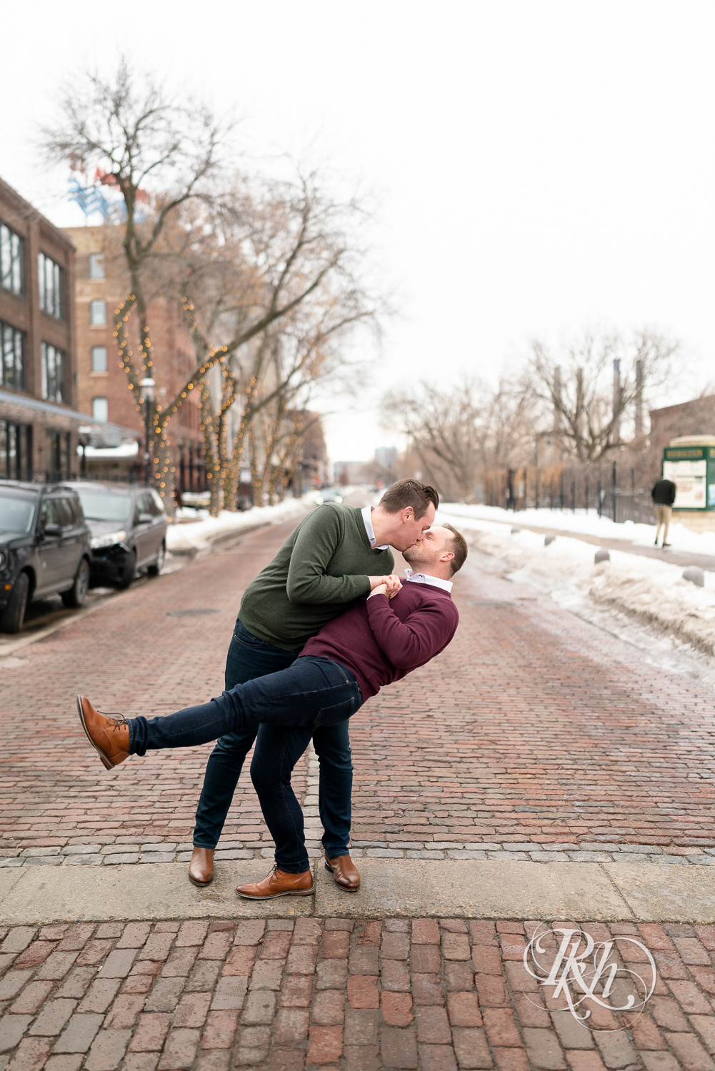 Gay men kiss on cobblestone street during the winter in Minneapolis, Minnesota.