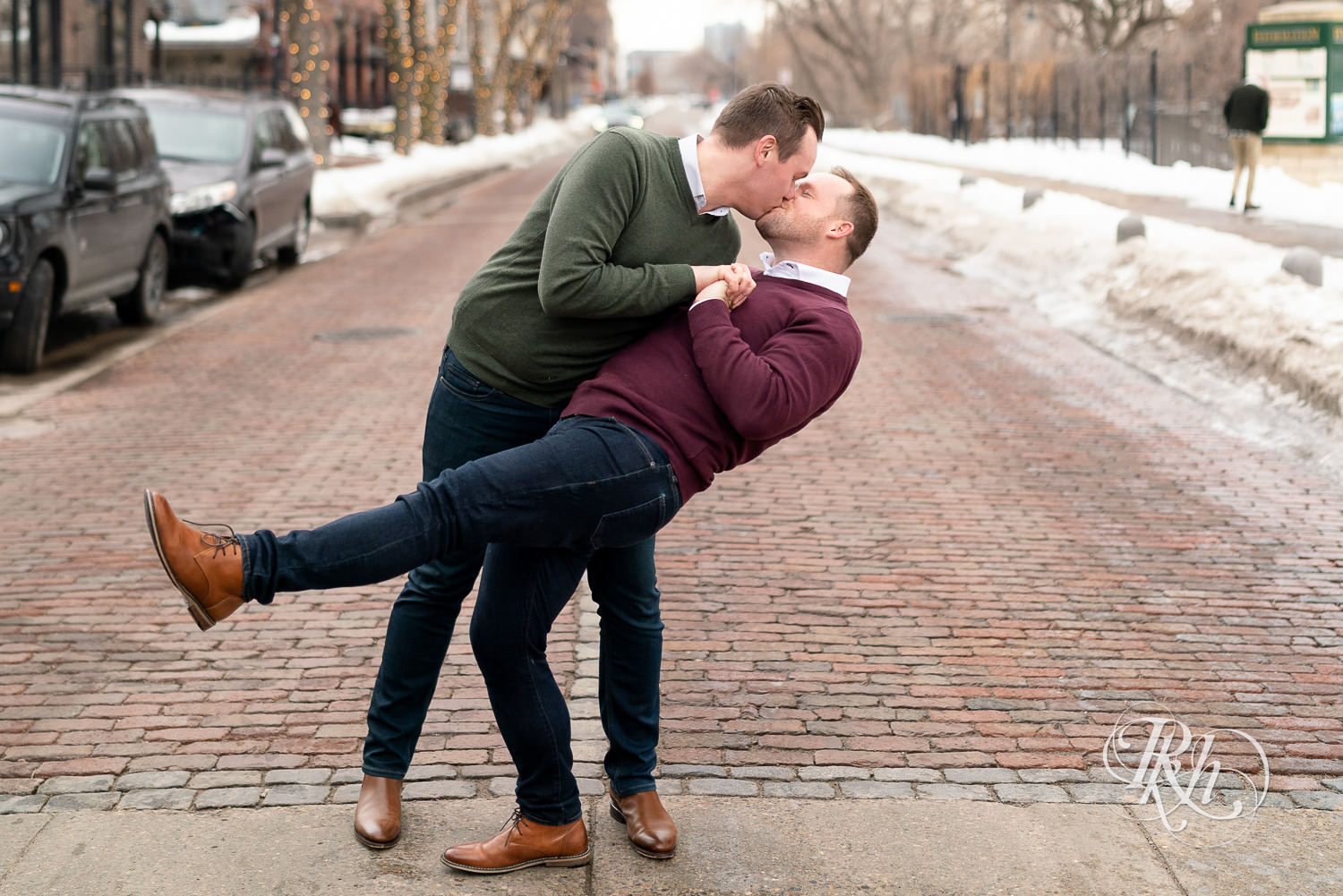 Gay men kiss on cobblestone street during the winter in Minneapolis, Minnesota.