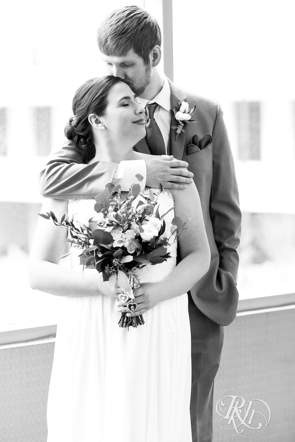 Groom kisses bride on head at Doubletree Hilton Saint Paul in Saint Paul, Minnesota.