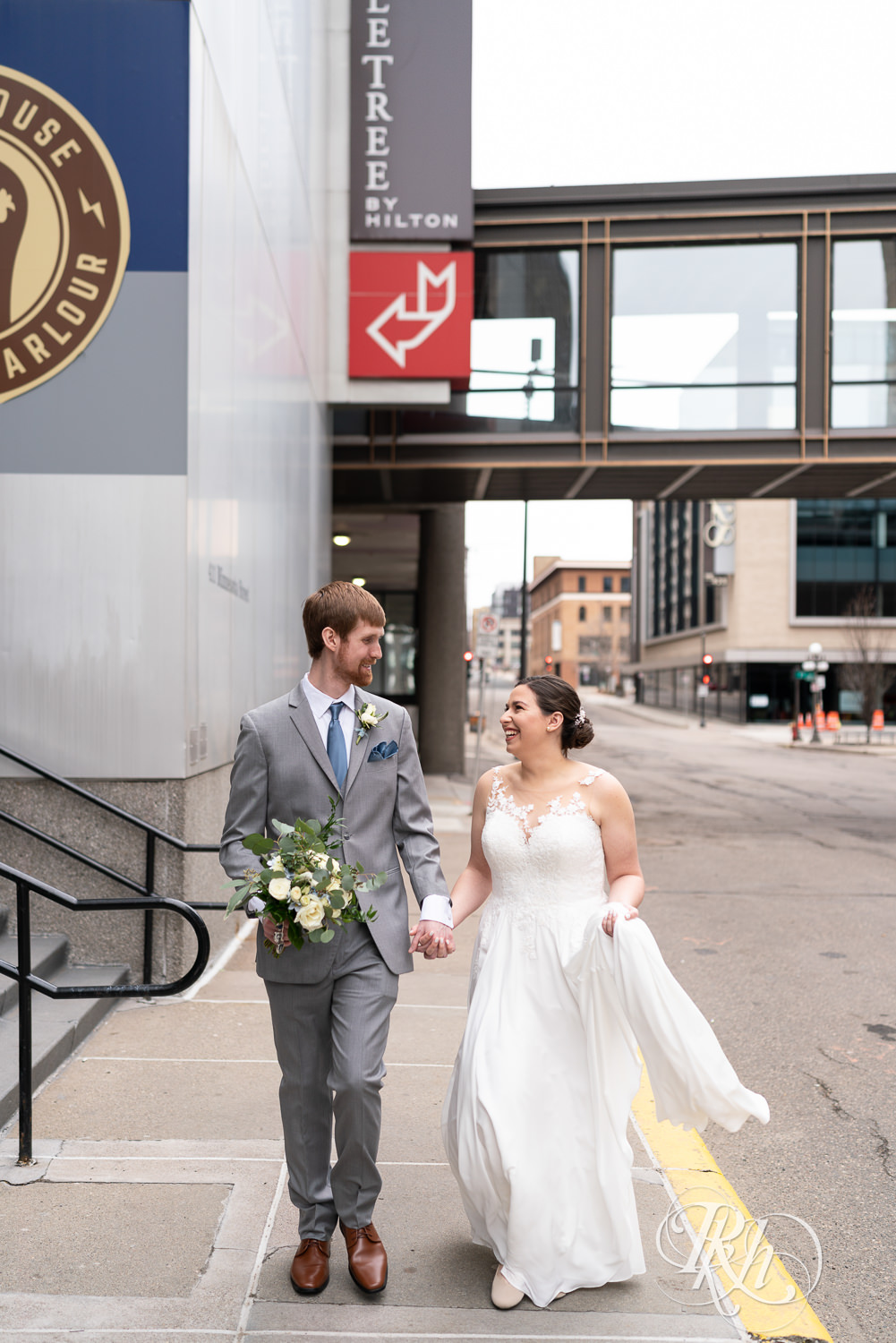 Bride and groom smile while walking down the street in Saint Paul, Minnesota.