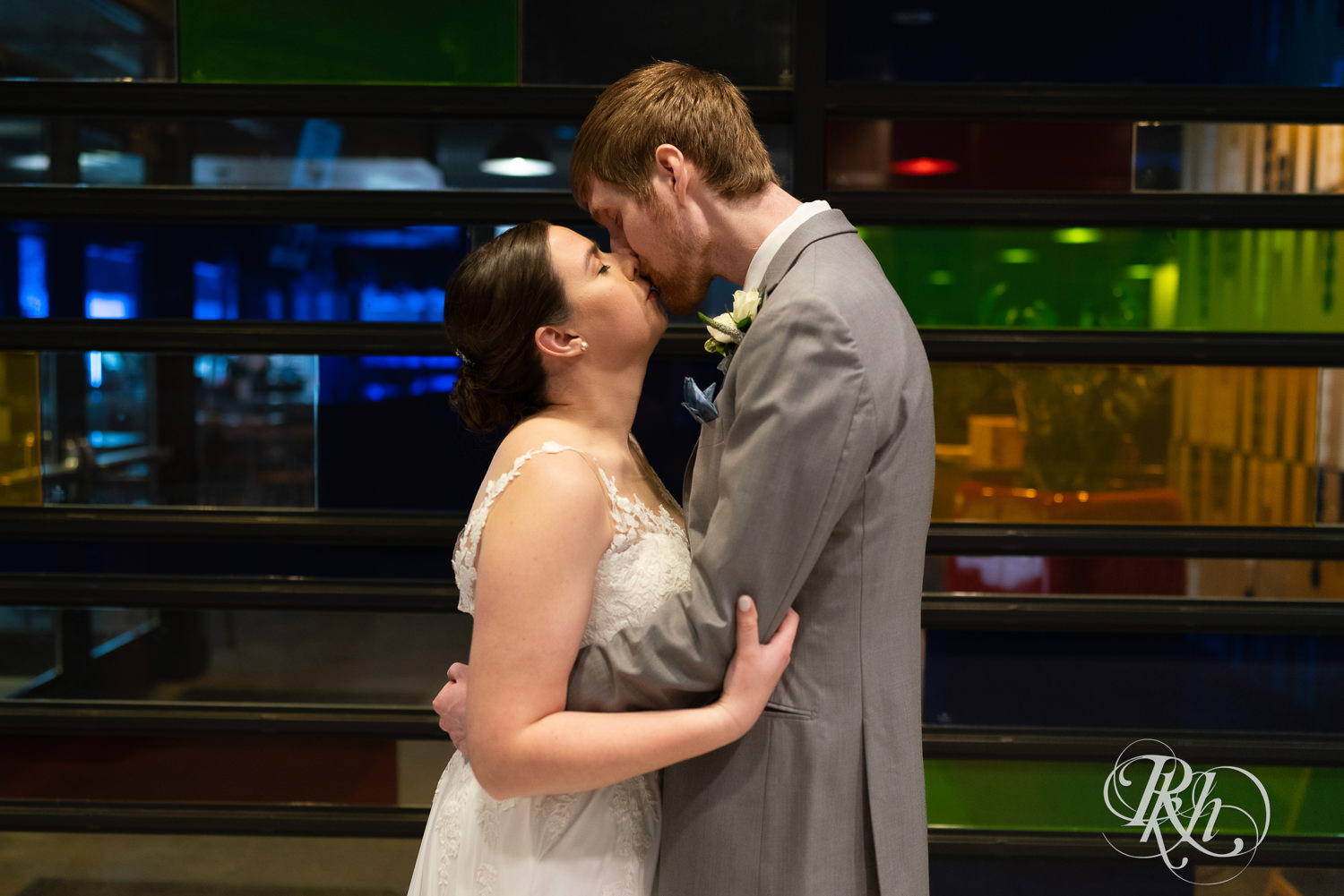 Bride and groom kiss in front of colorful wall at Doubletree Hilton Saint Paul in Saint Paul, Minnesota.