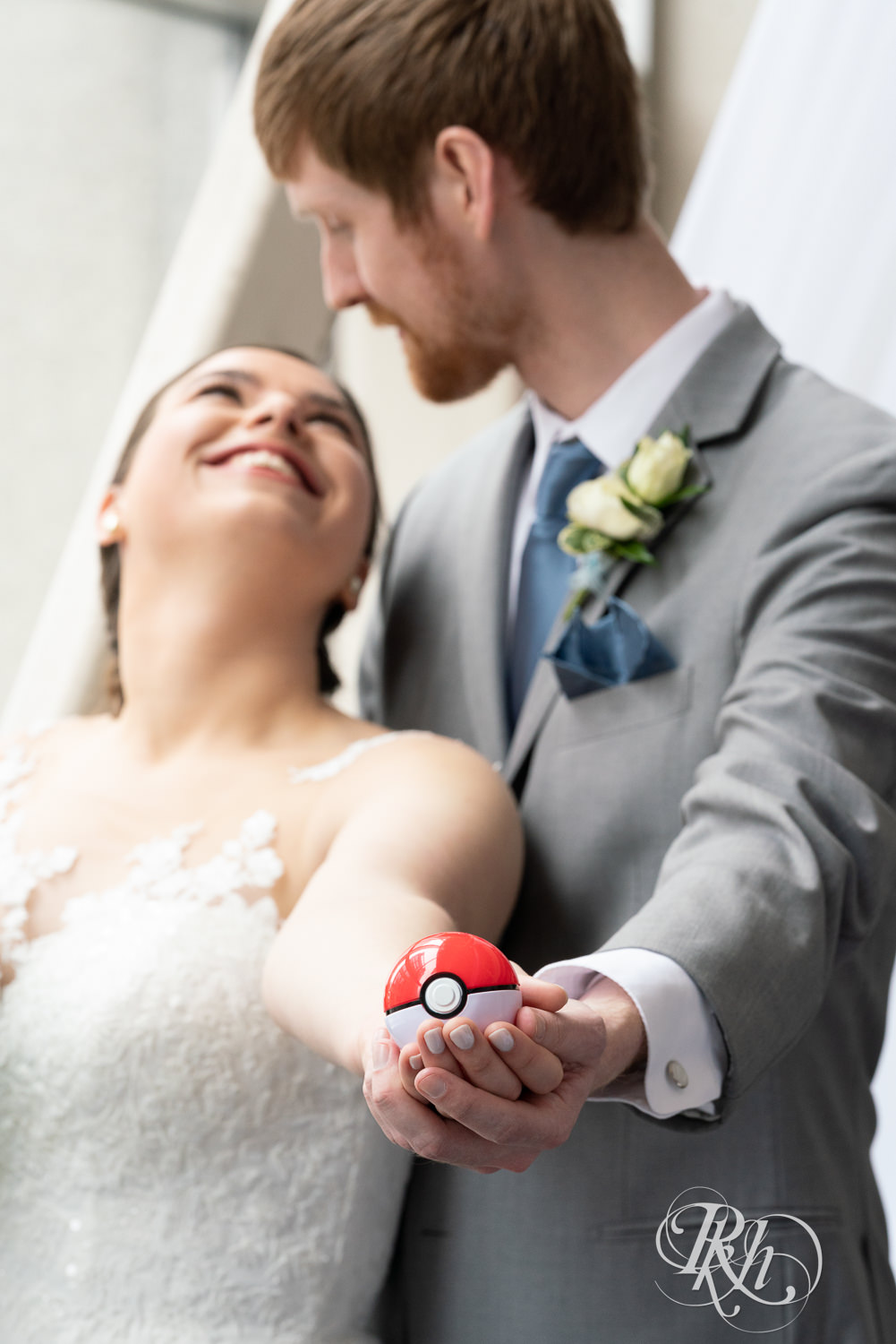 Bride and groom smile while holding Pokemon ball at Doubletree Hilton Saint Paul in Saint Paul, Minnesota.