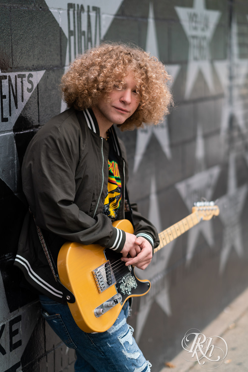 Senior boy playing guitar in front of First Avenue during downtown Minneapolis senior photography session.