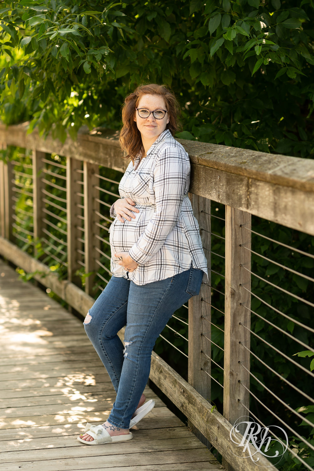 Pregnant woman holds belly at Lebanon Hills Regional Park in Eagan, Minnesota during maternity photography session.