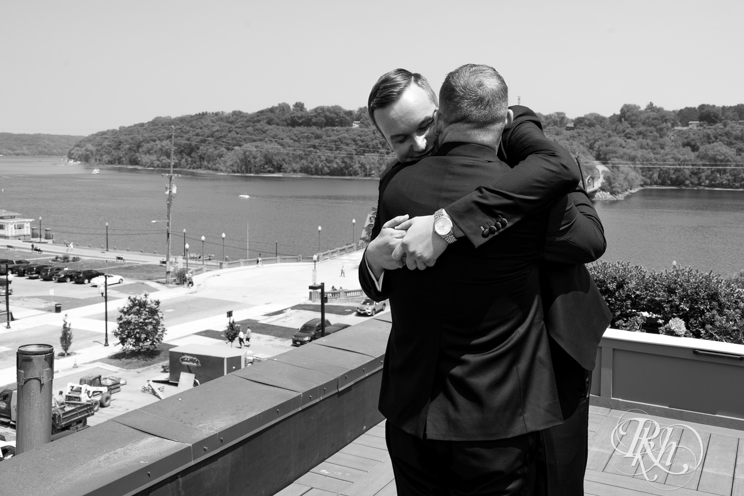 Grooms hug during first look on rooftop before gay wedding in Stillwater, Minnesota.