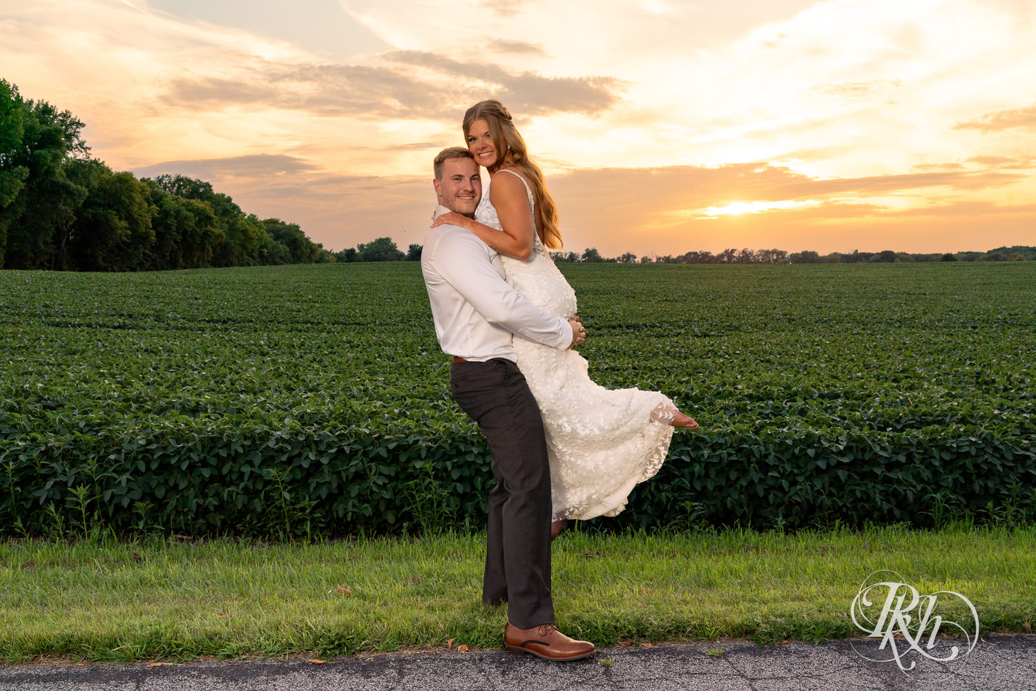 Groom lifts bride and they smile during sunset at Ahavah Cottage in Elysian, Minnesota.