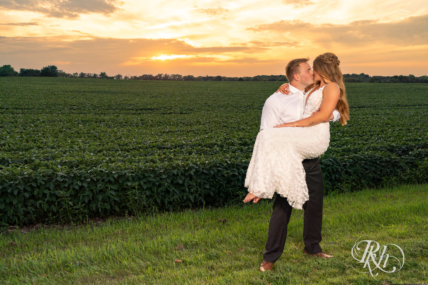 Groom lifts bride and they kiss during sunset at Ahavah Cottage in Elysian, Minnesota.