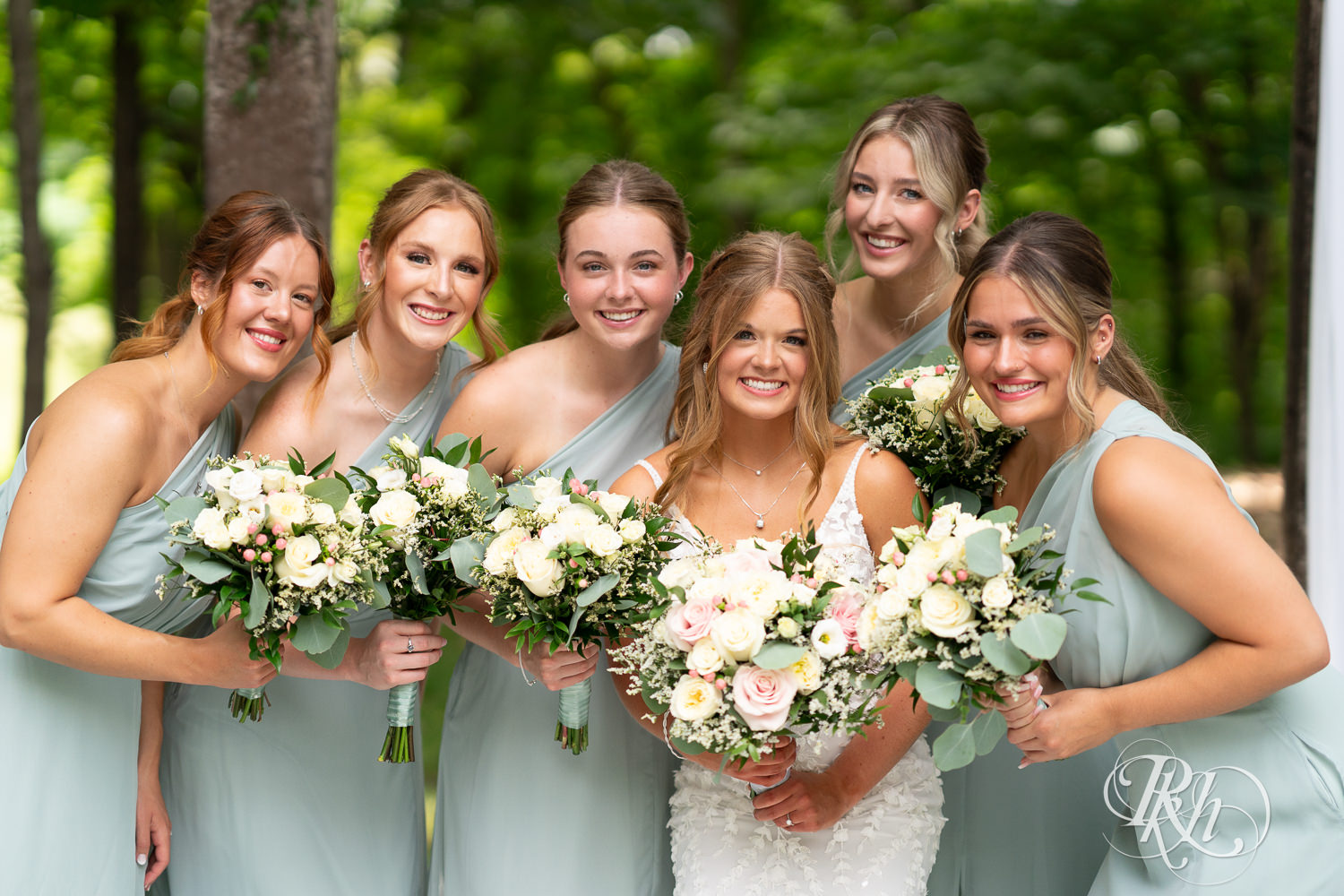 Bride smiles with wedding party on wedding day at Ahavah Cottage in Elysian, Minnesota.