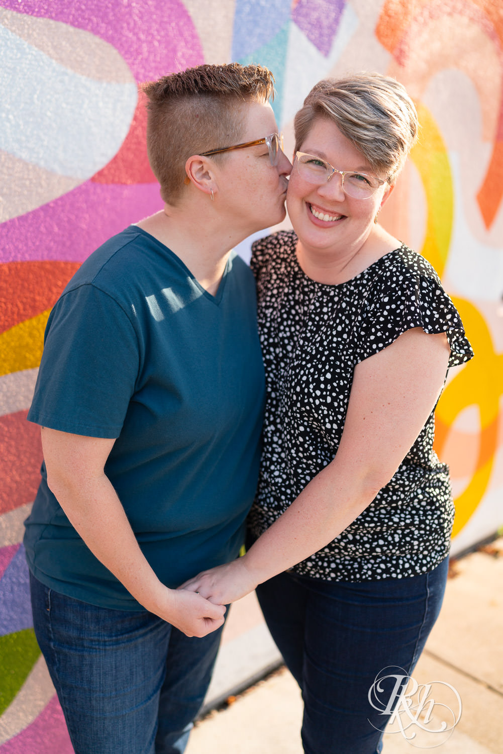 Lesbian couple smile and kiss during engagement photos in Saint Paul, Minnesota.