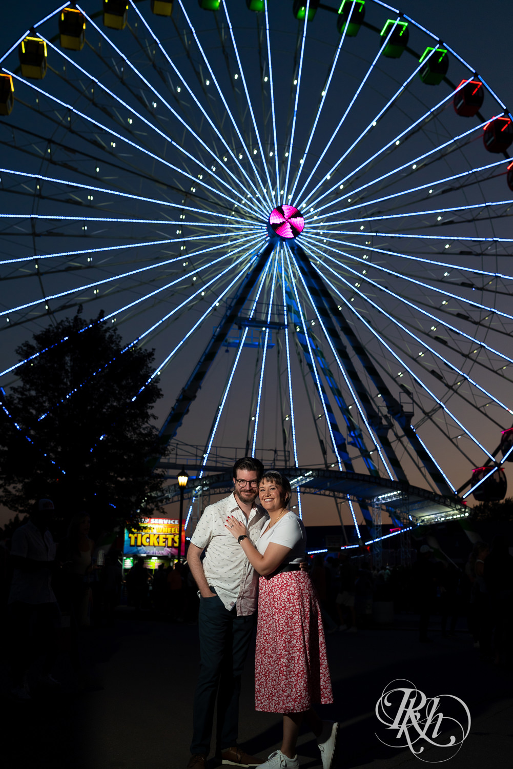 Man and woman smiling at night during their engagement photography at the Minnesota State Fair. 