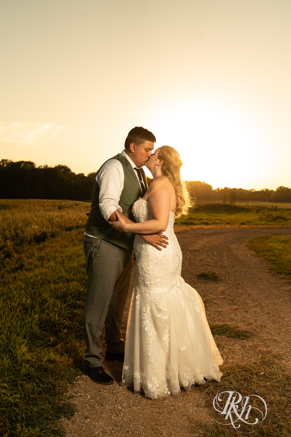 Bride and groom kiss at sunset on wedding day at Cottage Farmhouse in Glencoe, Minnesota.