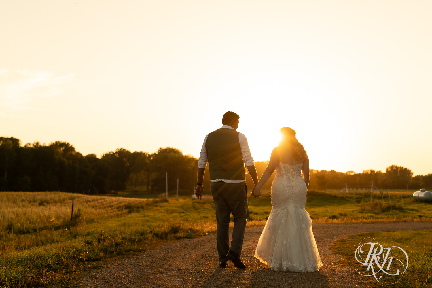 Bride and groom walk into sunset on wedding day at Cottage Farmhouse in Glencoe, Minnesota.