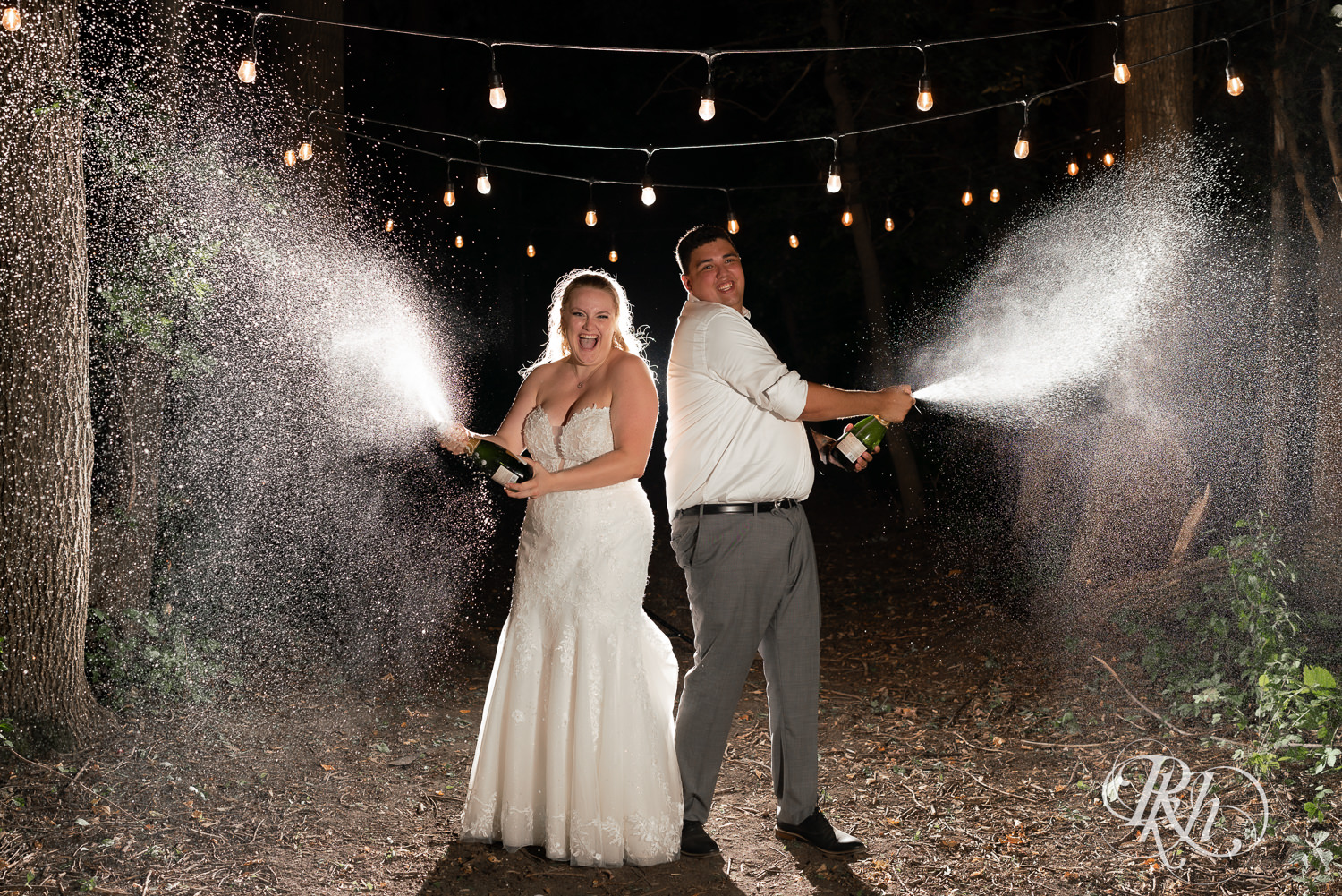 Bride and groom spray champagne at night at Cottage Farmhouse in Glencoe, Minnesota.