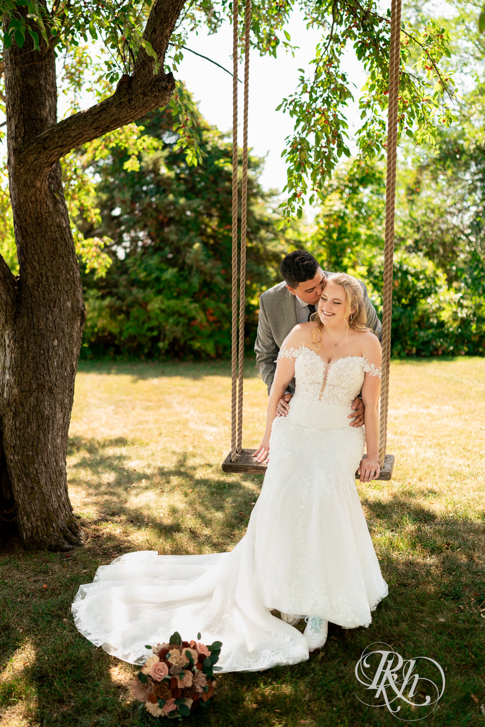 Bride and groom kiss on swing on wedding day at Cottage Farmhouse in Glencoe, Minnesota.
