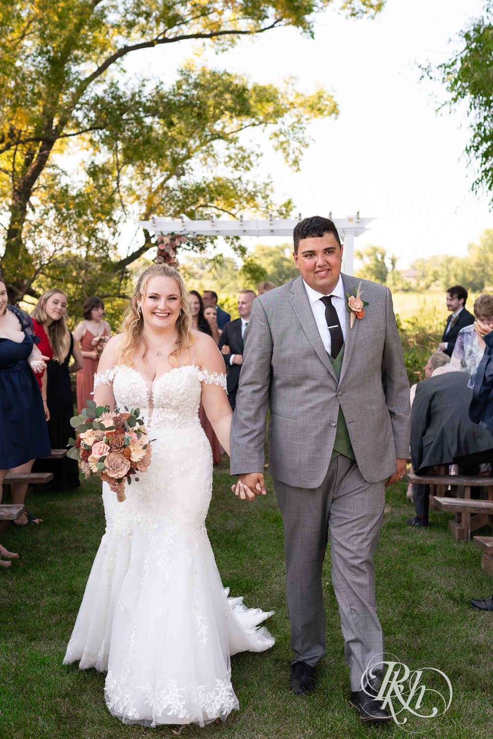 Bride and groom smile during summer wedding ceremony at Cottage Farmhouse in Glencoe, Minnesota.