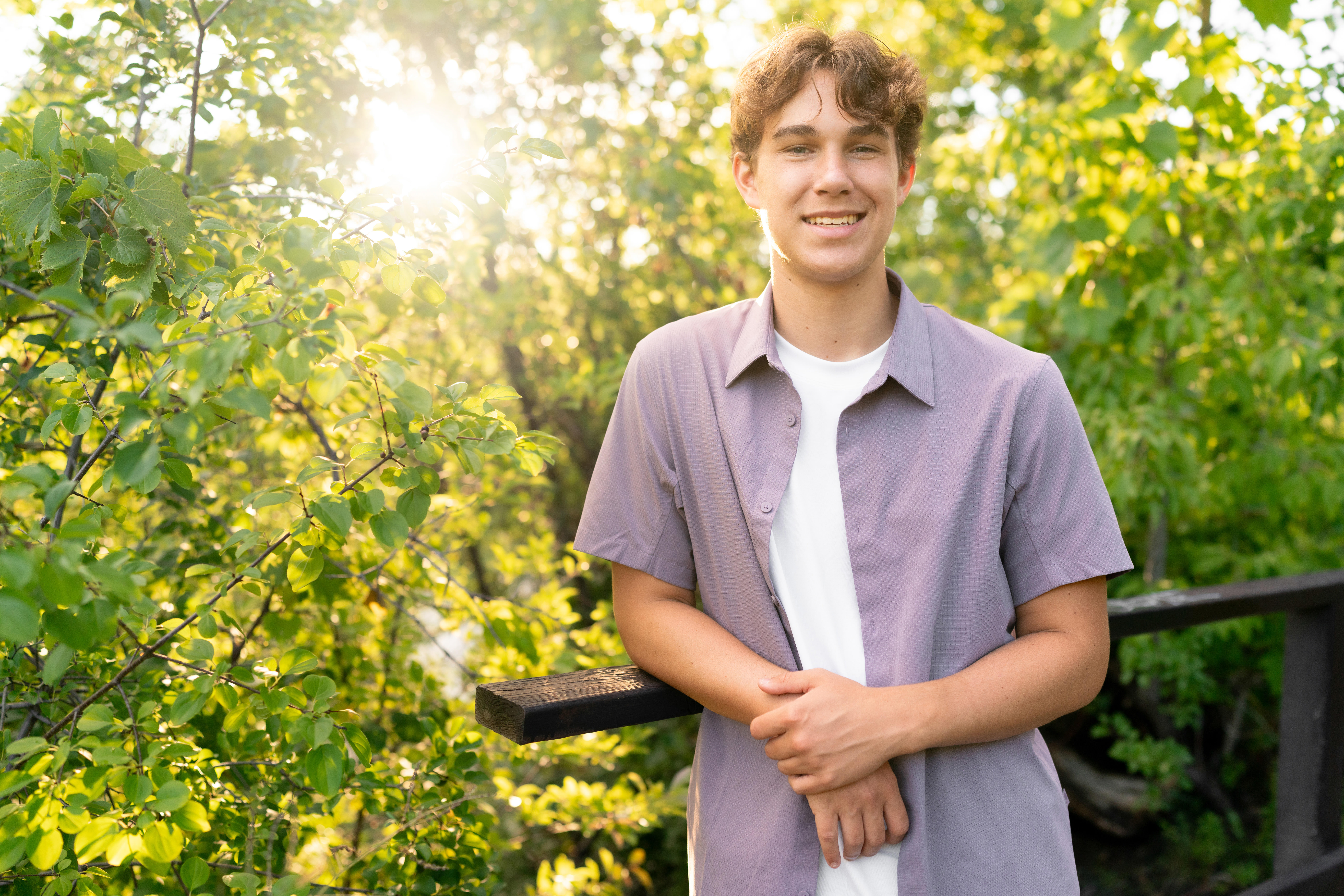 High school boy smiles during senior photography in Mill City and the Stone Arch Bridge in Minneapolis, Minnesota.