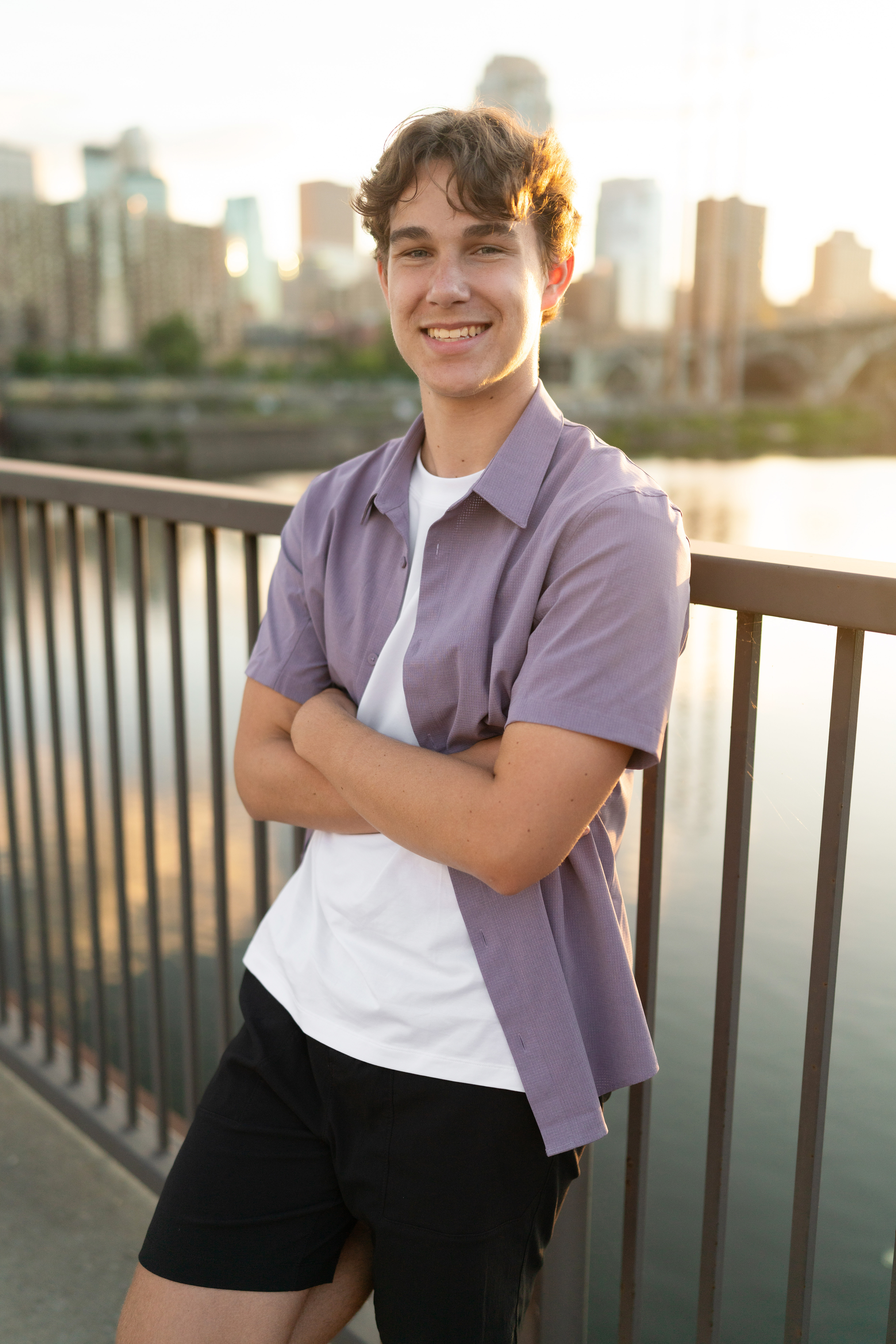 High school boy smiles during senior photography in Mill City and the Stone Arch Bridge in Minneapolis, Minnesota.