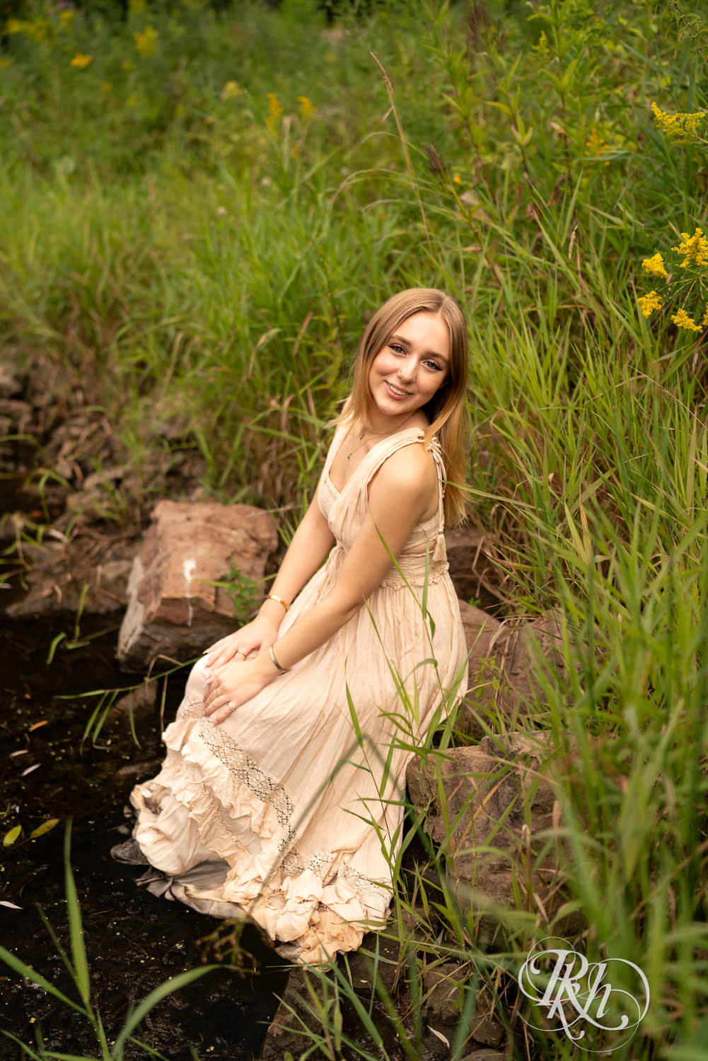 Blond girl in sundress smiles during senior photography in Minnetonka, Minnesota.