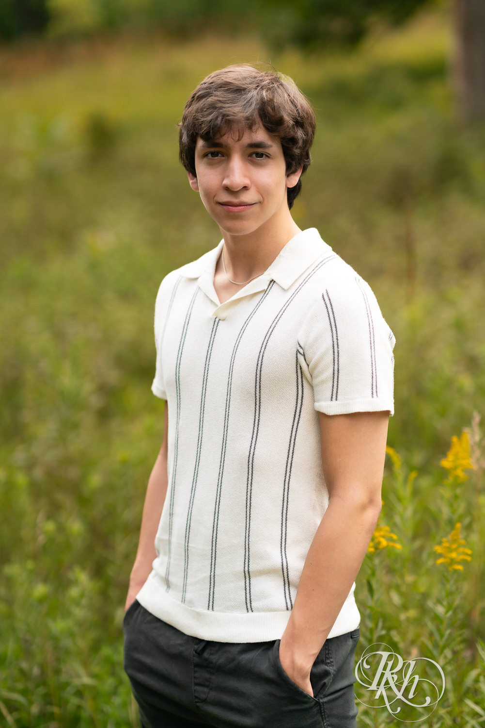 High school senior boy smiles during senior photography at Old Mill Park in Hastings, Minnesota.