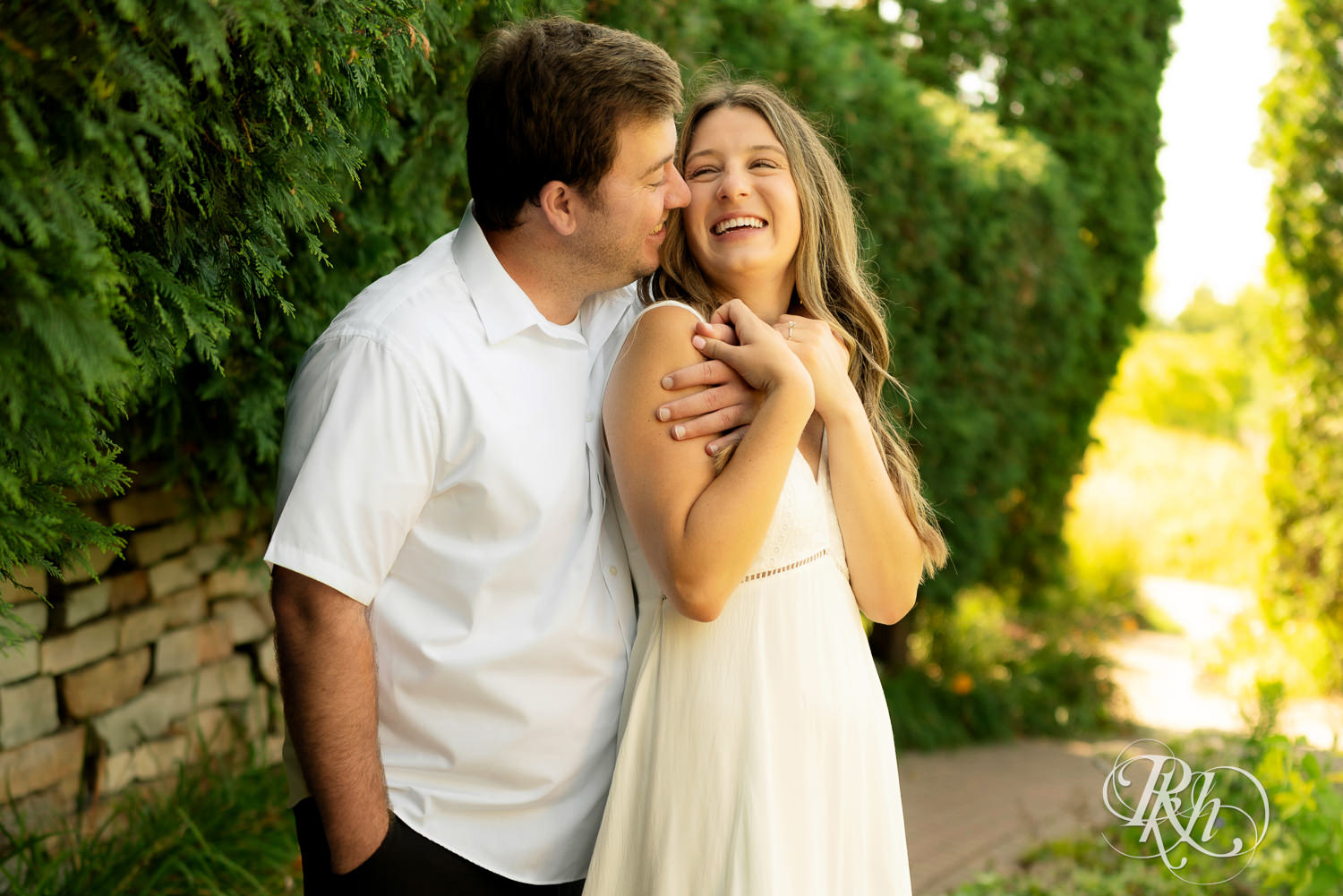 Man and woman in white dress laugh during engagement photography at Centennial Lakes Park in Edina, Minnesota.