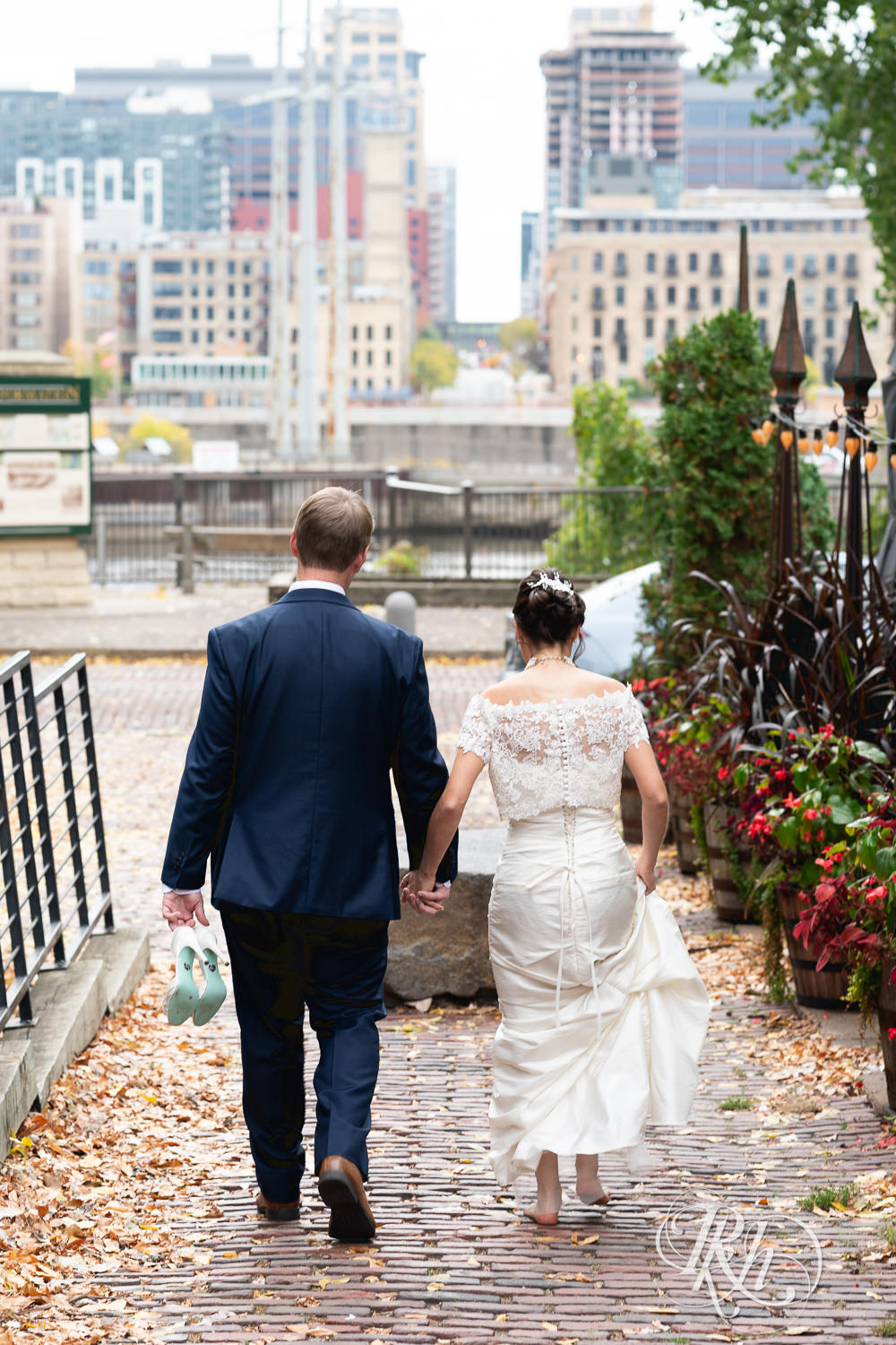 Bride and groom walk toward the city on wedding day at The Grand 1858 in Minneapolis, Minnesota.