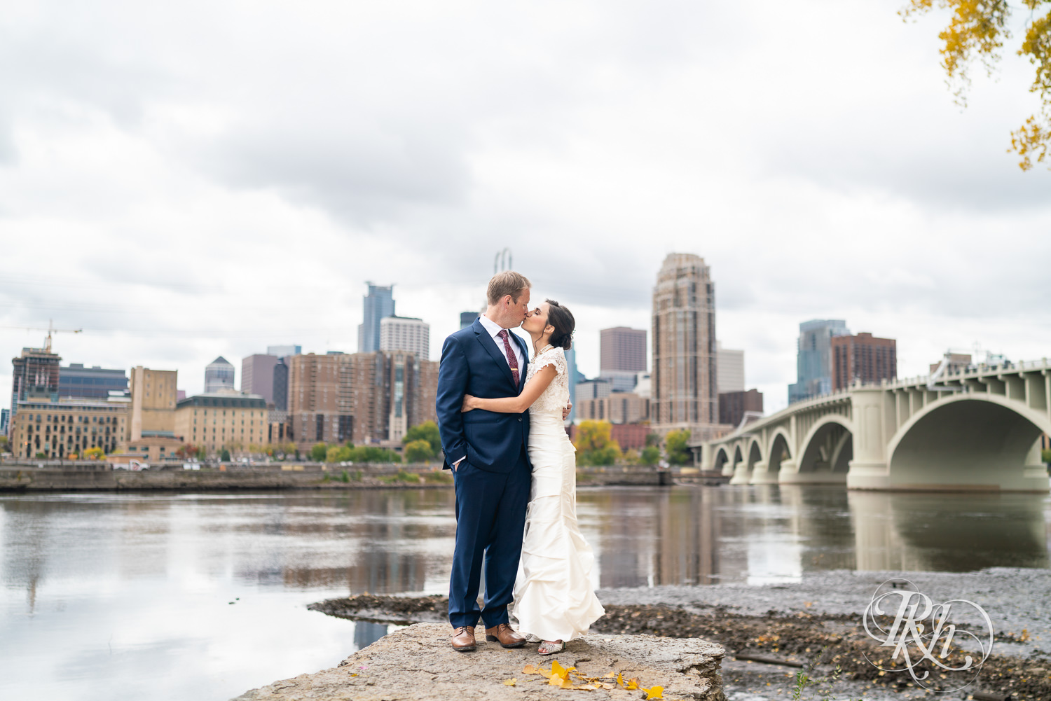 Bride and groom kiss in front of the Minneapolis skyline.