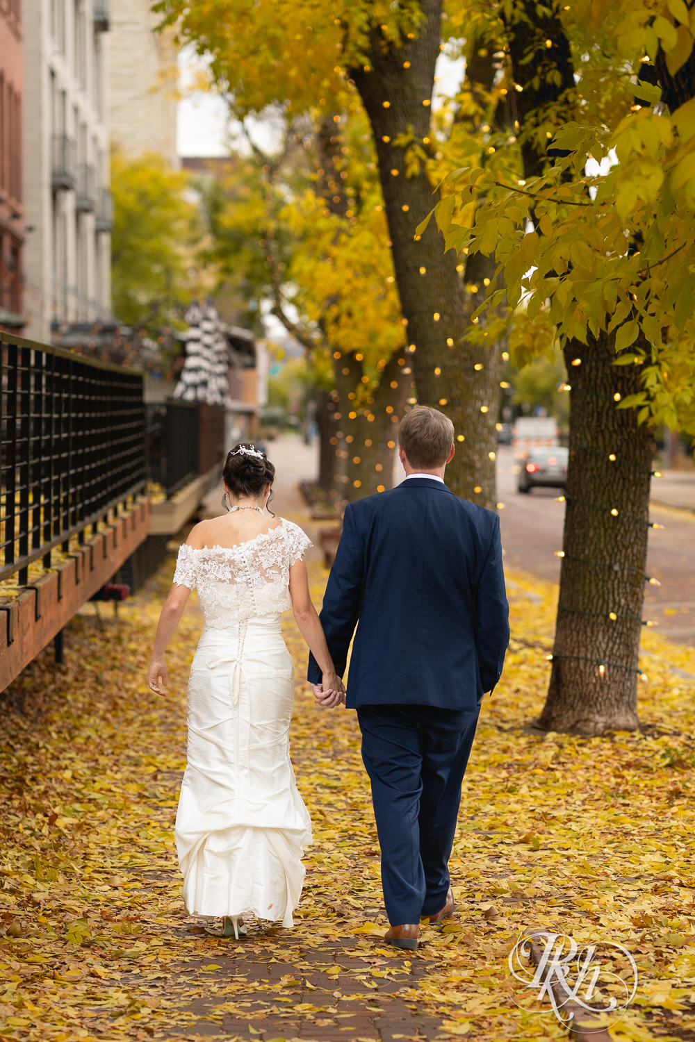 Bride and groom walk away from camera in Saint Anthony Main in Minneapolis, Minnesota.