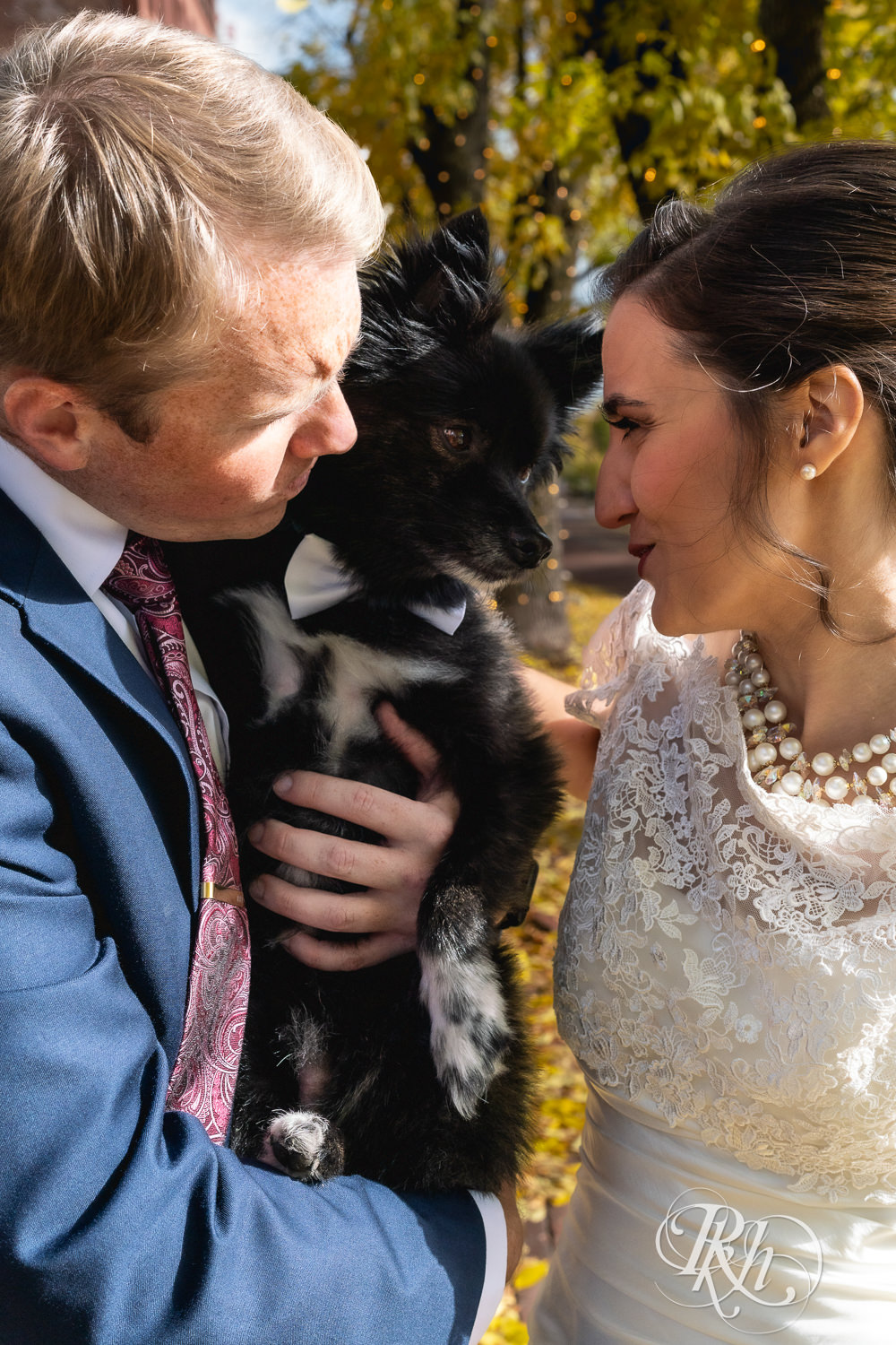 Bride and groom smile with their dog in Saint Anthony Main in Minneapolis, Minnesota.
