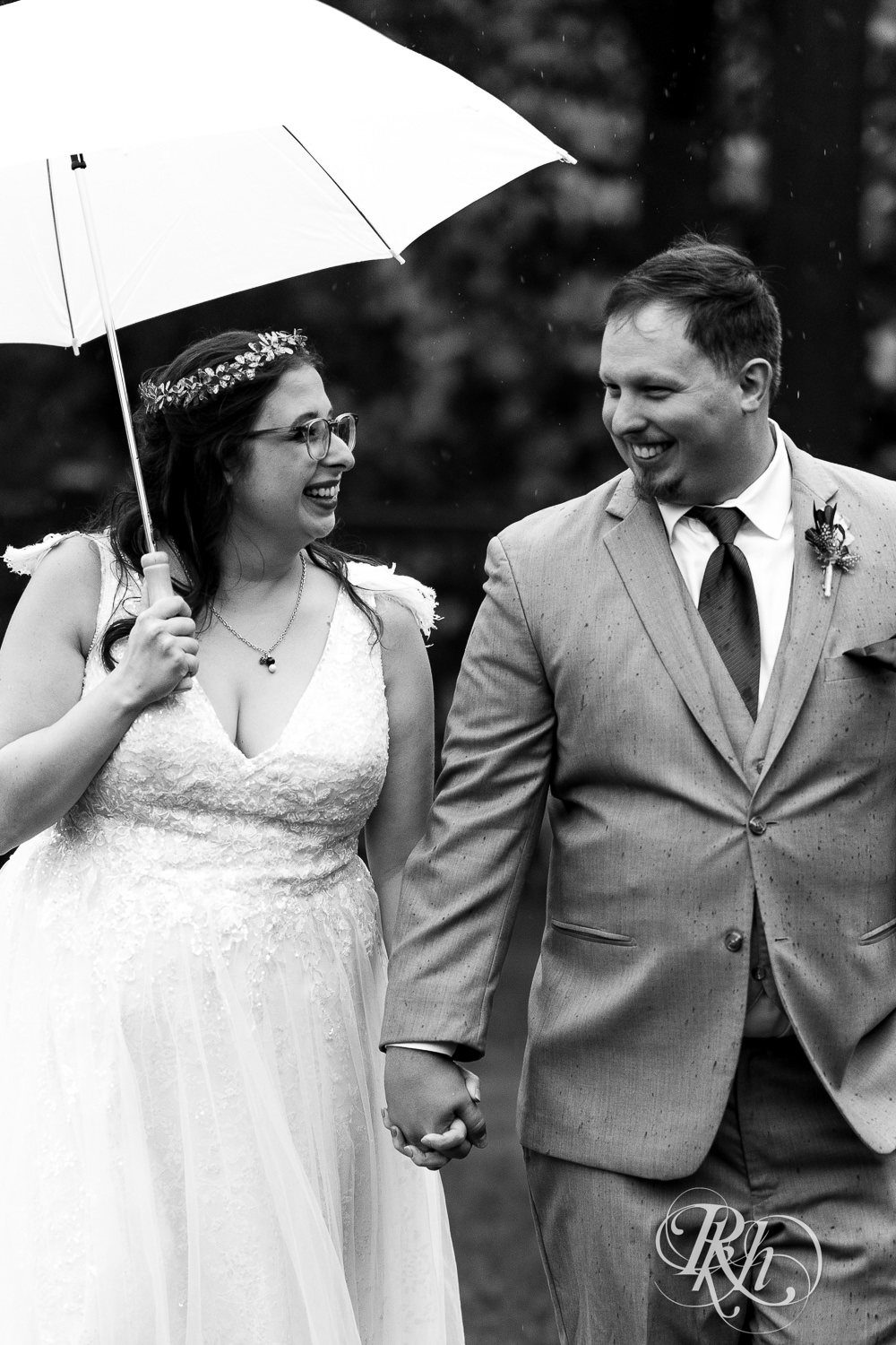 Bride and groom smile under the umbrella during rainy wedding day at Bunker Hills Event Center in Coon Rapids, Minnesota.