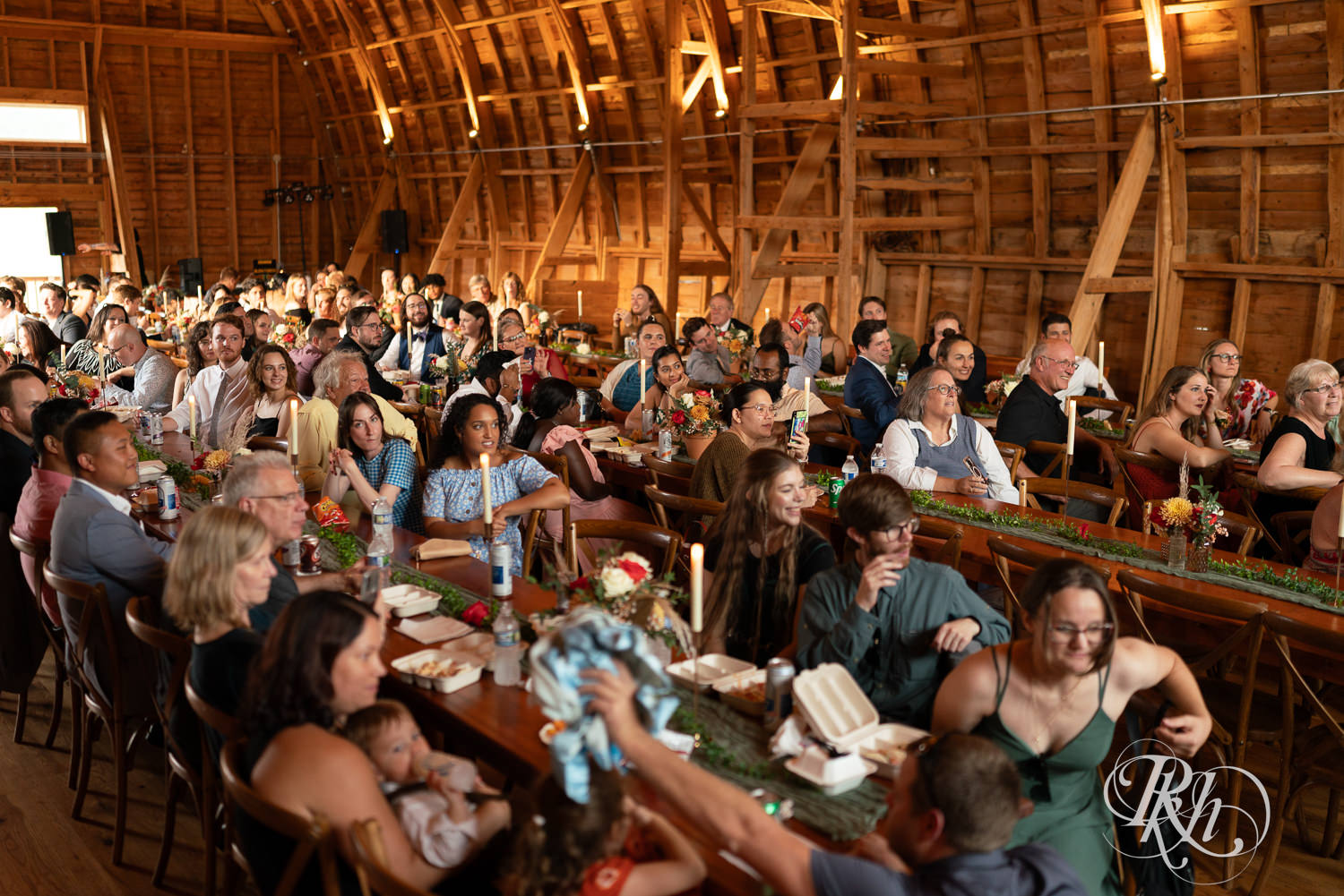 Guests smile during wedding reception at Hayvn at Hay River in Boyceville, Wisconsin. 