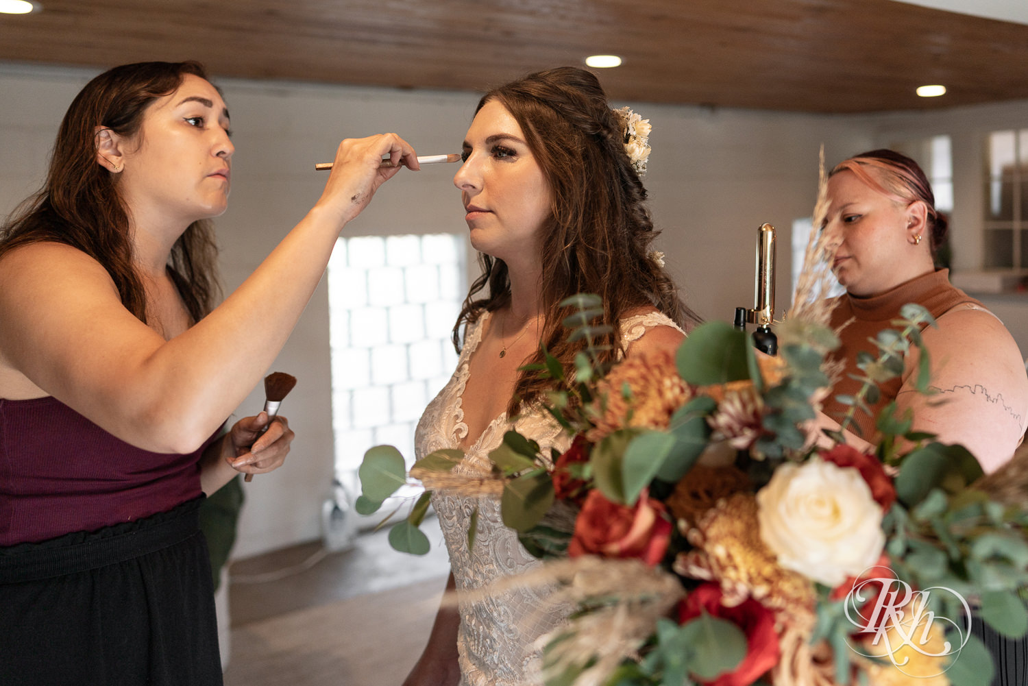 Bride getting makeup done on wedding day at Hayvn at Hay River in Boyceville, Wisconsin. 