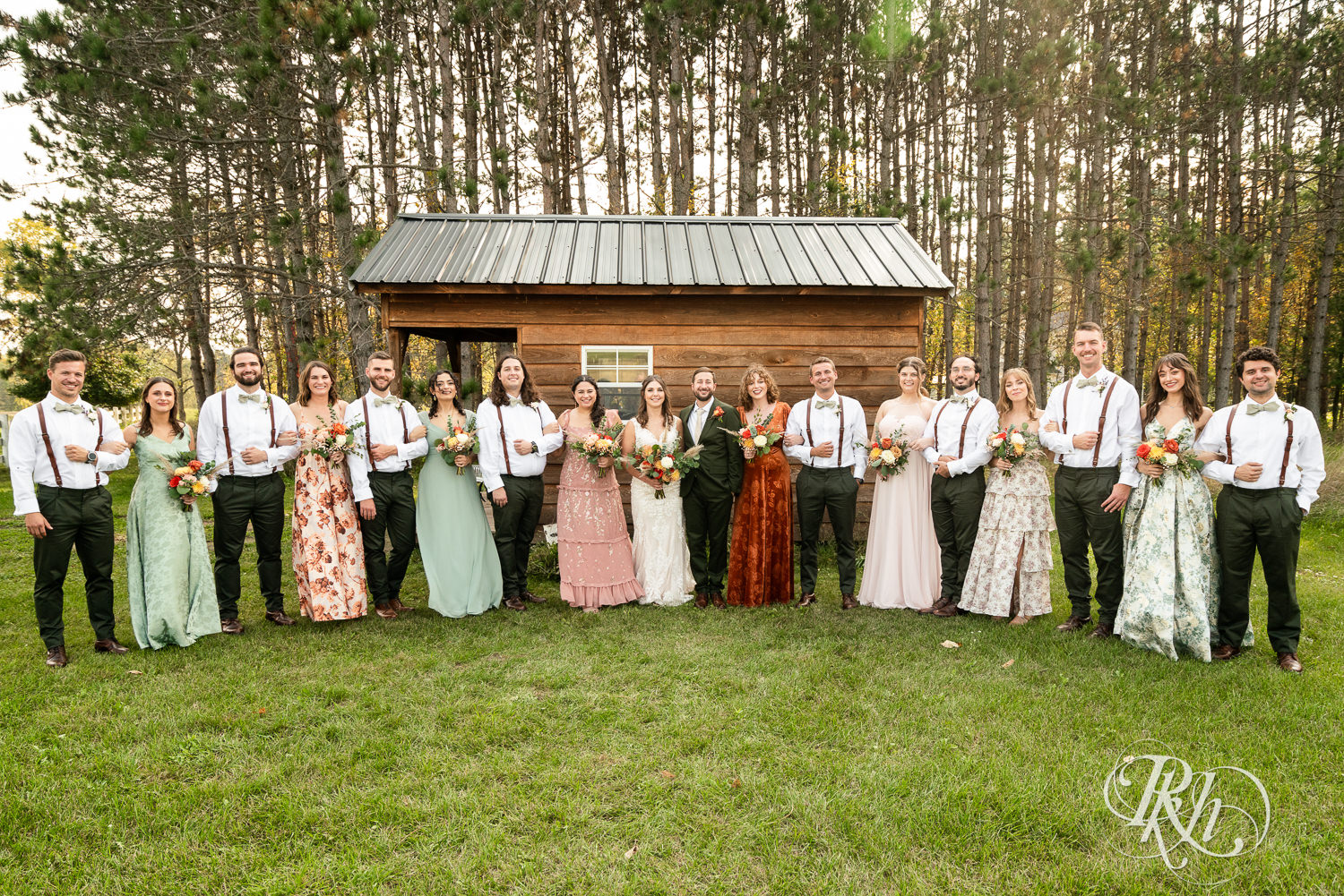 Bride and groom smile with wedding party on wedding day at Hayvn at Hay River in Boyceville, Wisconsin. 