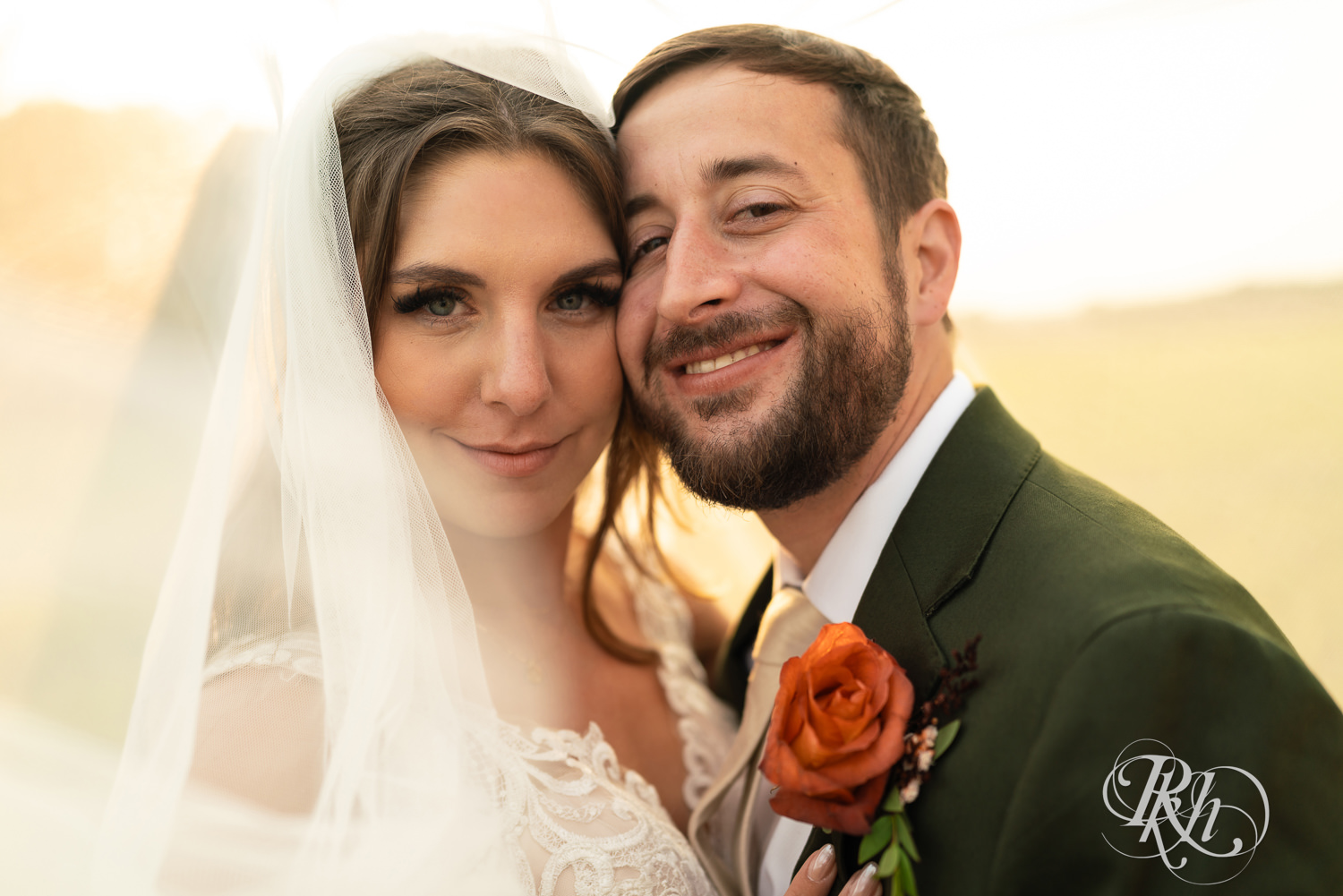 Bride and groom smile under veil in the sunset at Hayvn at Hay River in Boyceville, Wisconsin. 
