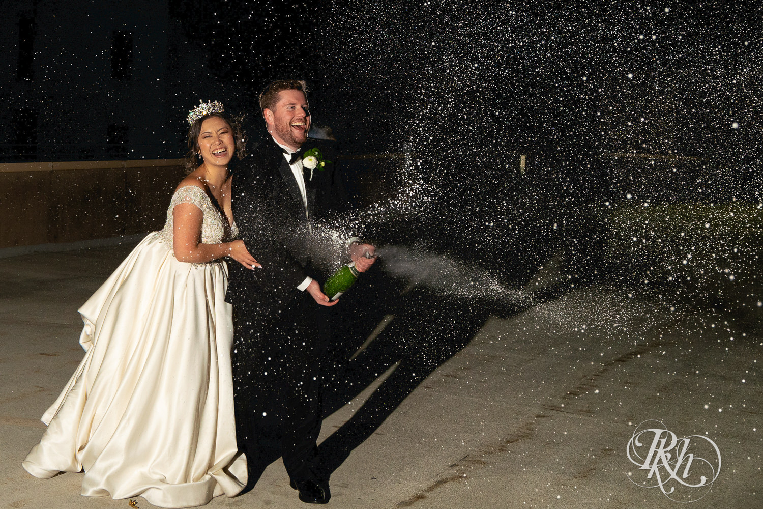 Hmong bride and groom spray champagne on a rooftop in Saint Paul, Minnesota.