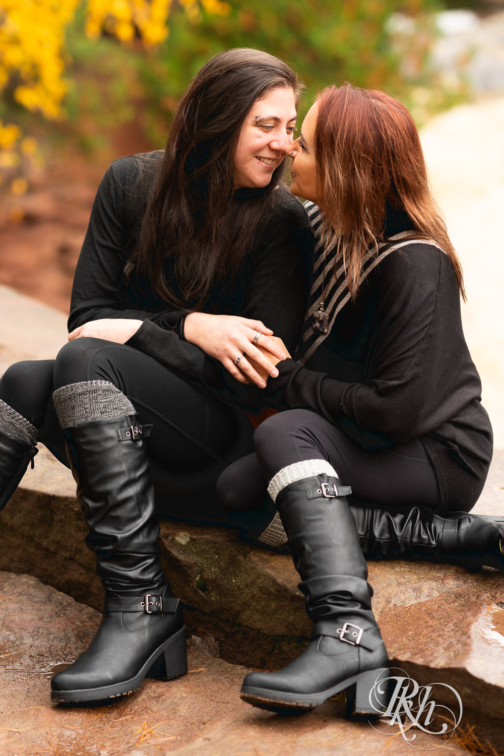 Lesbian couple smiles during fall engagement photos at Amnicon Falls in Wisconsin. 