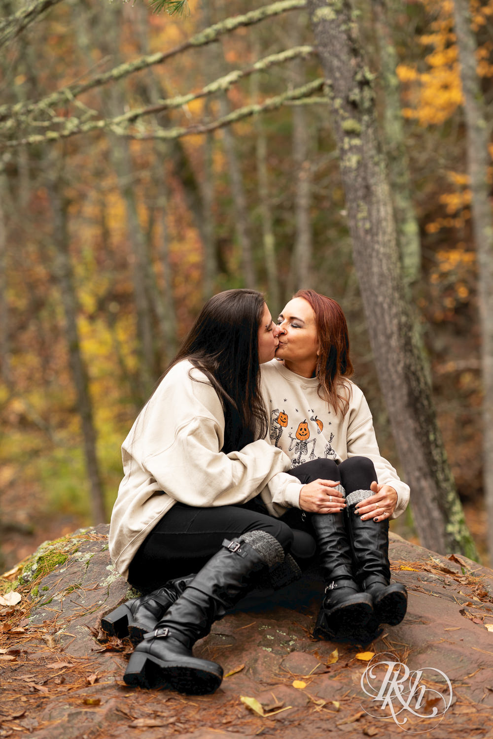 Lesbian couple kiss during fall engagement photos at Amnicon Falls in Wisconsin. 