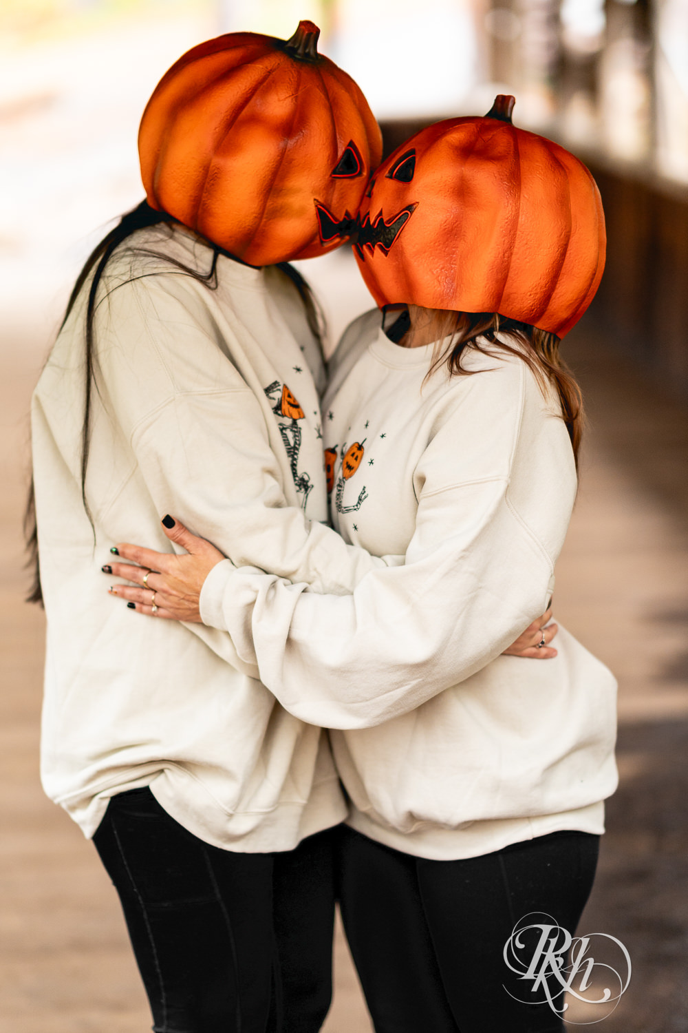 Lesbian couple pose in pumpkin heads during Halloween engagement photos at Amnicon Falls in Wisconsin. 