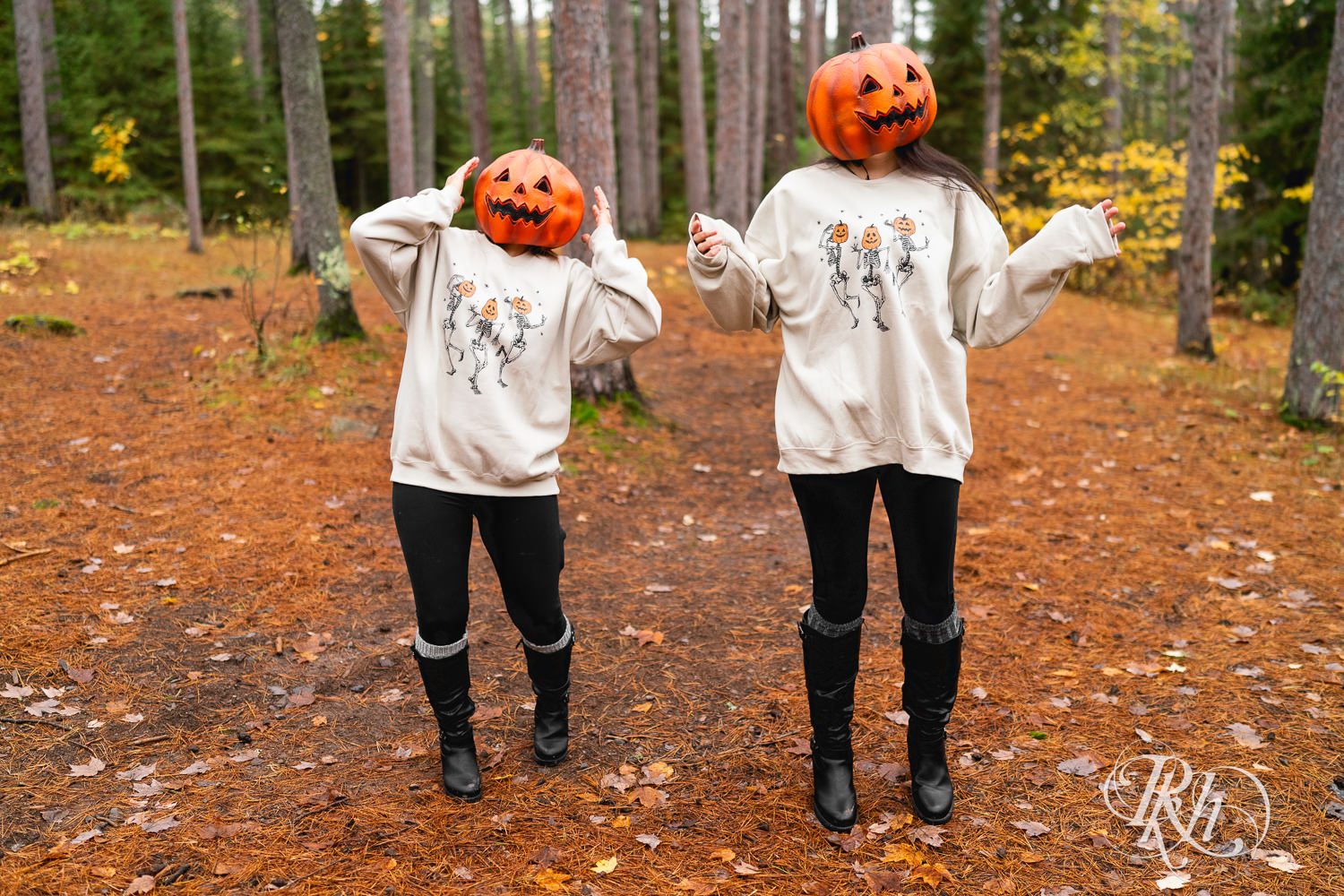 Lesbian couple dance in pumpkin heads during Halloween engagement photos at Amnicon Falls in Wisconsin. 