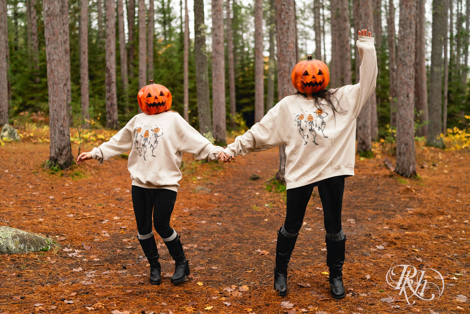 Lesbian couple dance in pumpkin heads during Halloween engagement photos at Amnicon Falls in Wisconsin. 