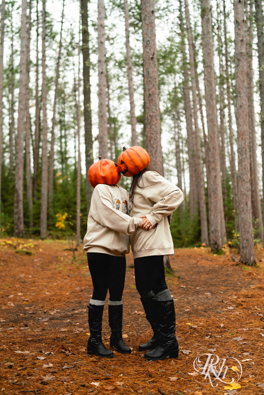 Lesbian couple kiss in pumpkin heads during Halloween engagement photos at Amnicon Falls in Wisconsin. 